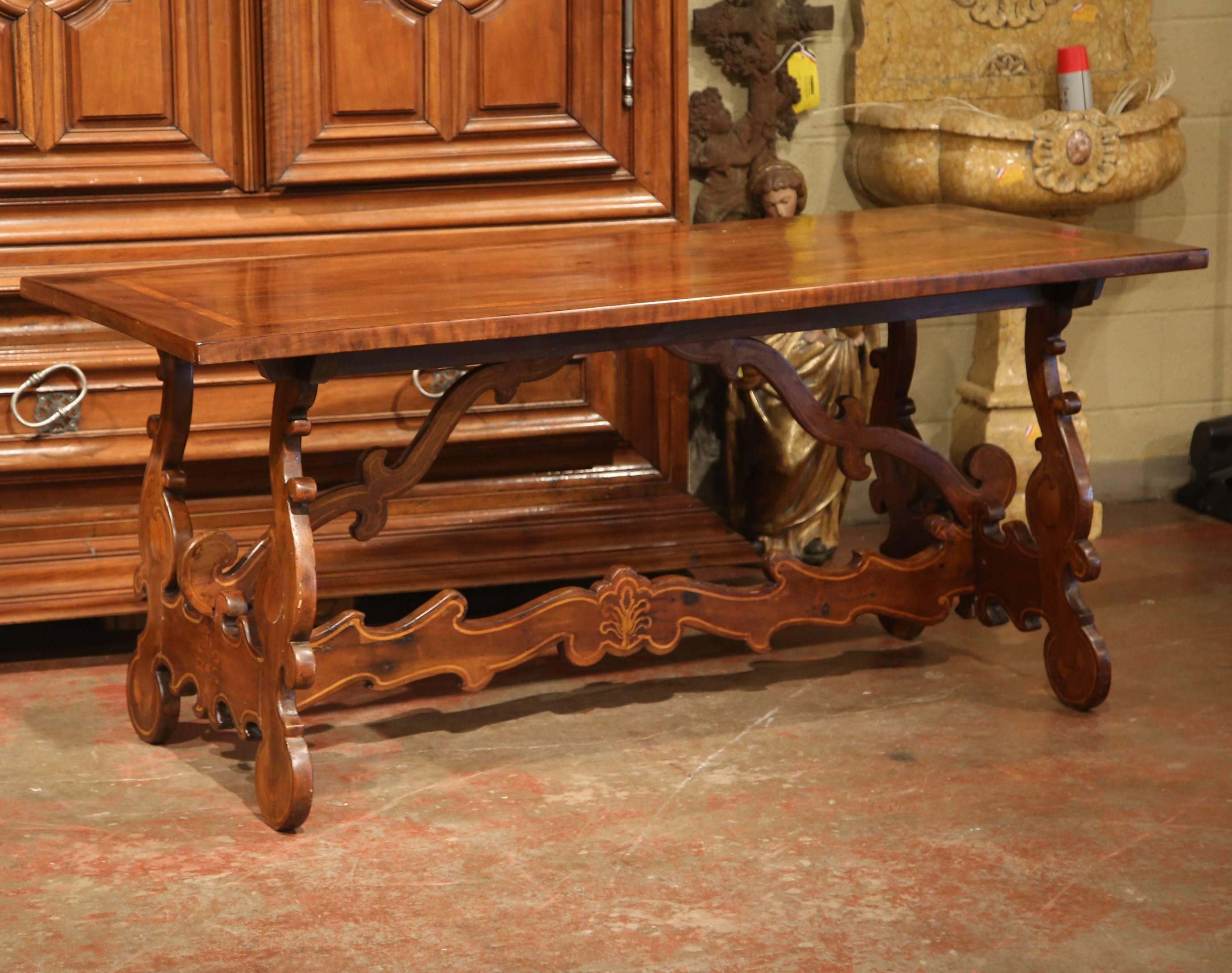 This elegant, antique fruit wood dining room table was crafted in Italy, circa 1830. The intricate table features a solid top made from a single walnut plank and embellished with a decorative inlay cherry band around the perimeter. The base has two