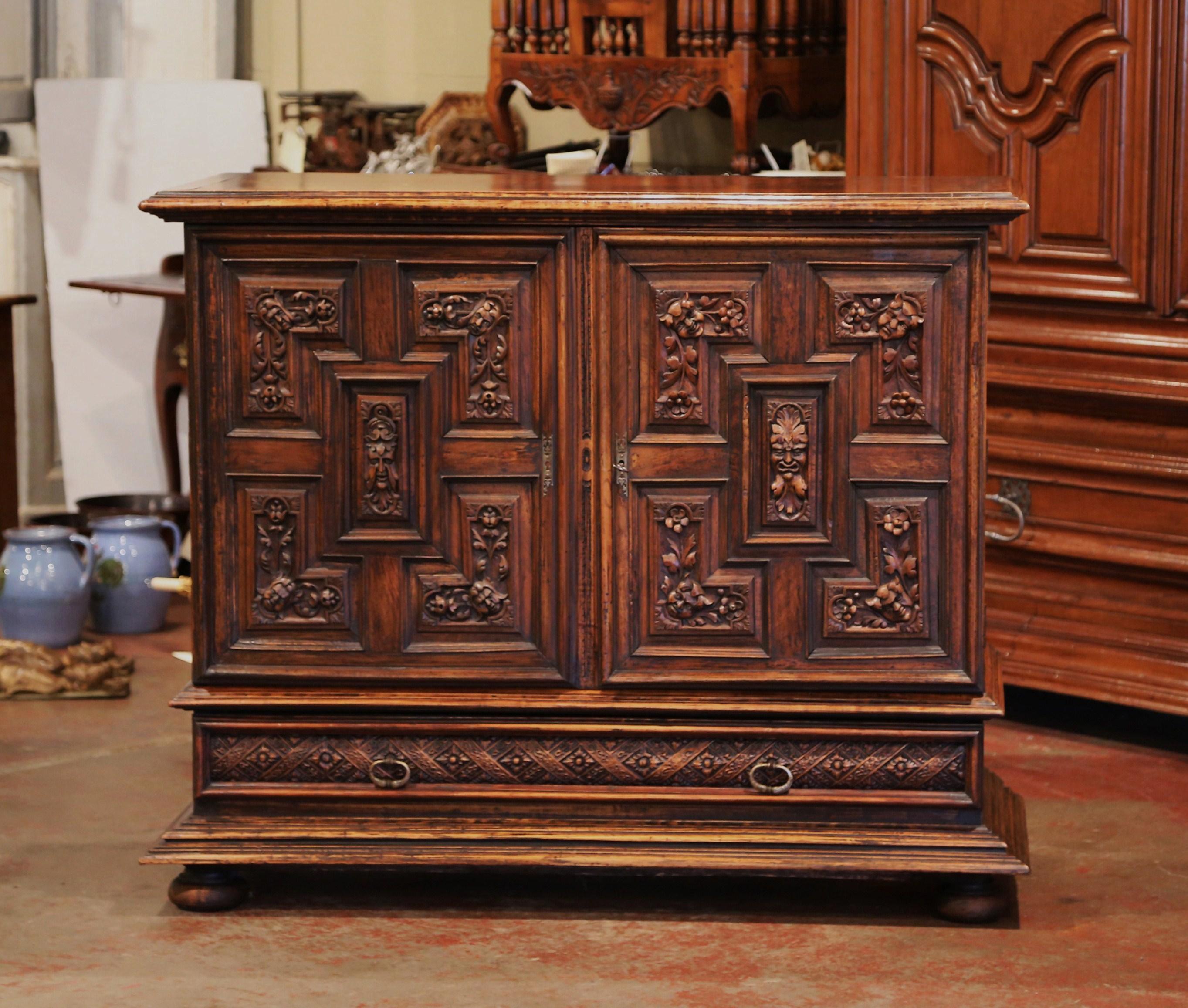 This elegant carved cabinet was crafted in Italy, circa 1860, made of walnut, the tall fruitwood buffet stands on bun feet, and features two heavily carved doors with chocolate raised panels decorated with foliage and head figures. When open, the