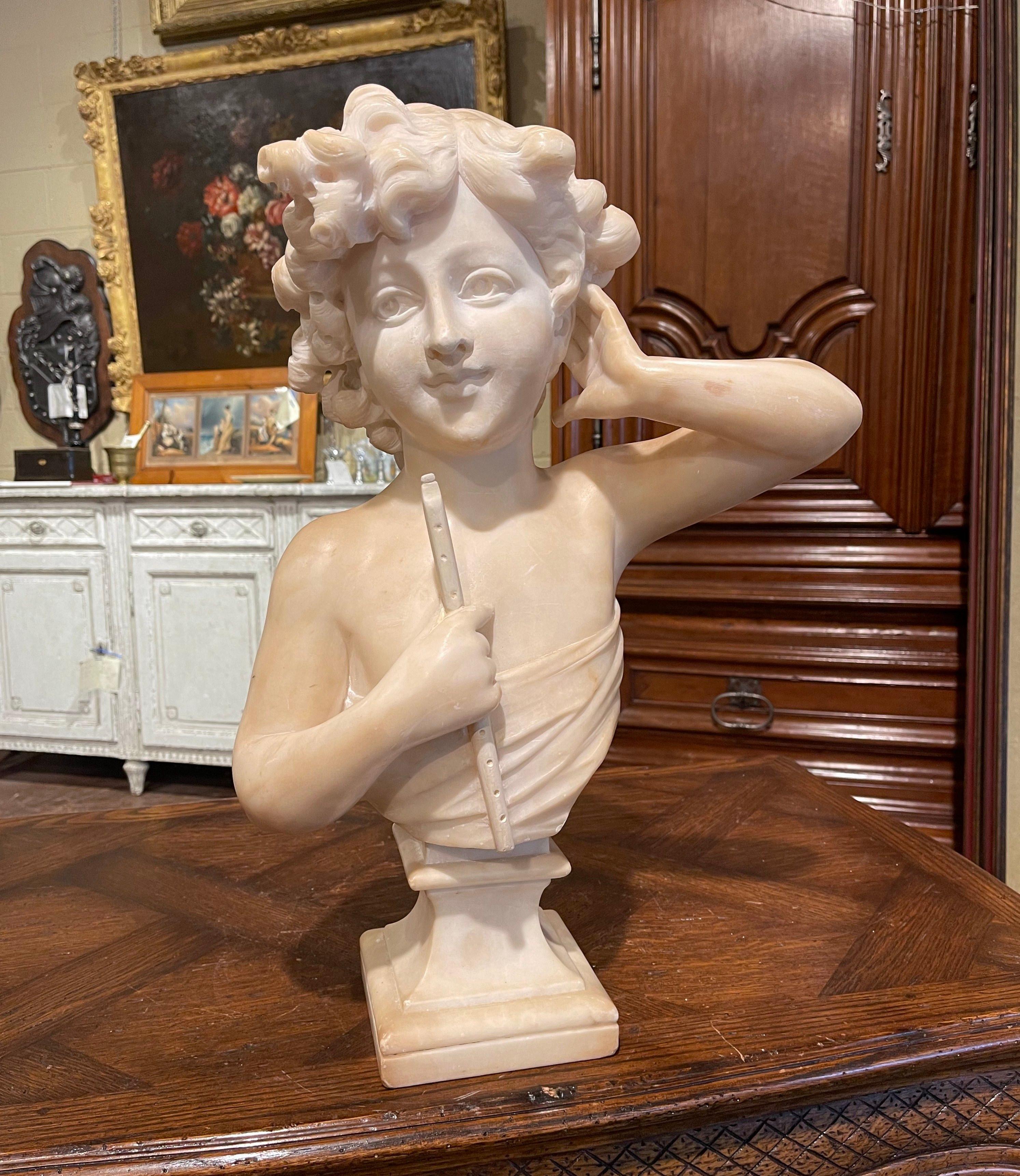 Crafted in Italy circa 1890, this antique marbles sculpture stands on a separate and swivel square base, and depicts a young girl holding a transverse flute in one hand, while holding her neck with the other. The bust, signed on the back by the