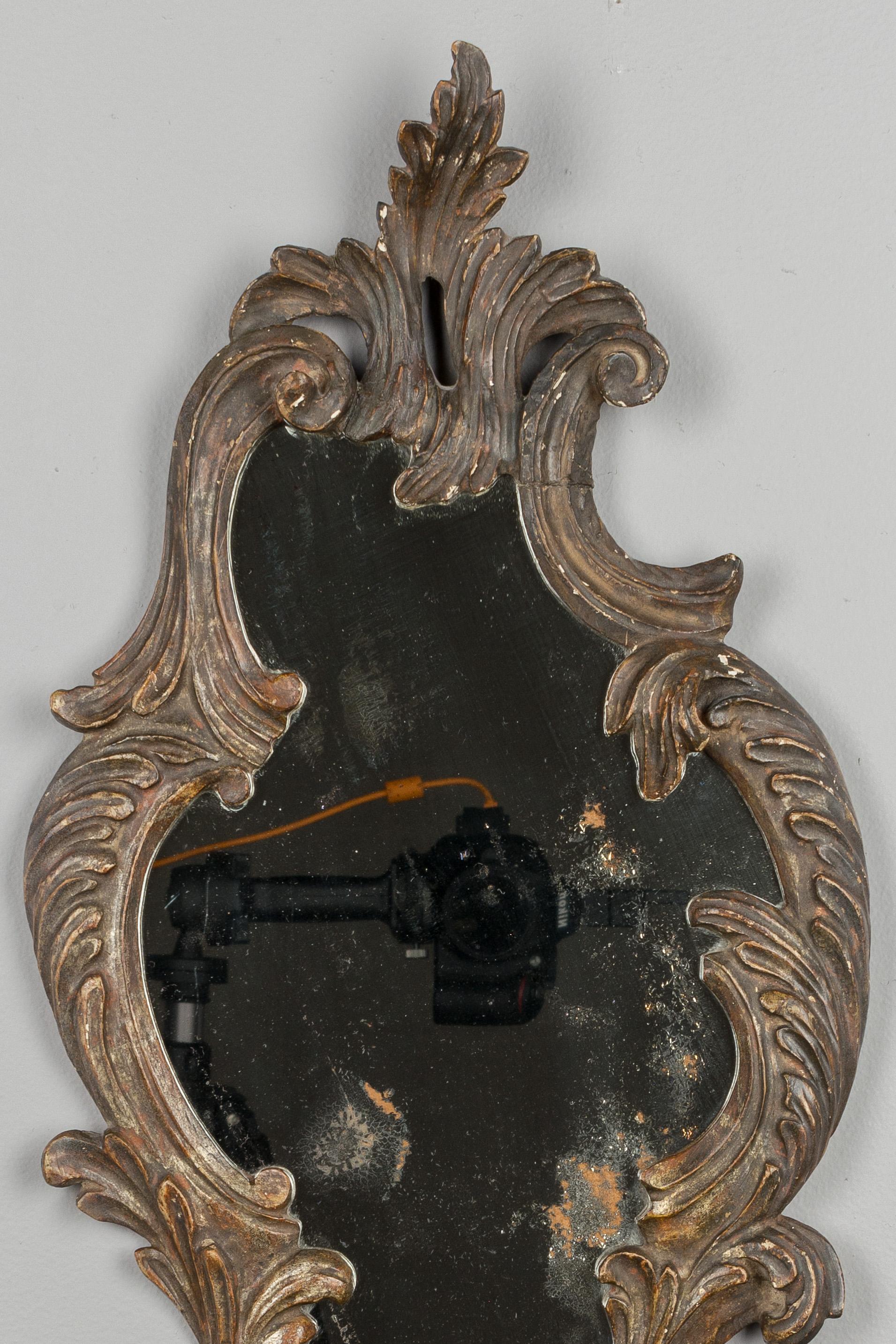 Kleiner italienischer Barockspiegel aus dem 19. Jahrhundert mit dekorativ geschnitztem Holzrahmen. Originaler Spiegel mit alter Versilberung. Schöne Patina.