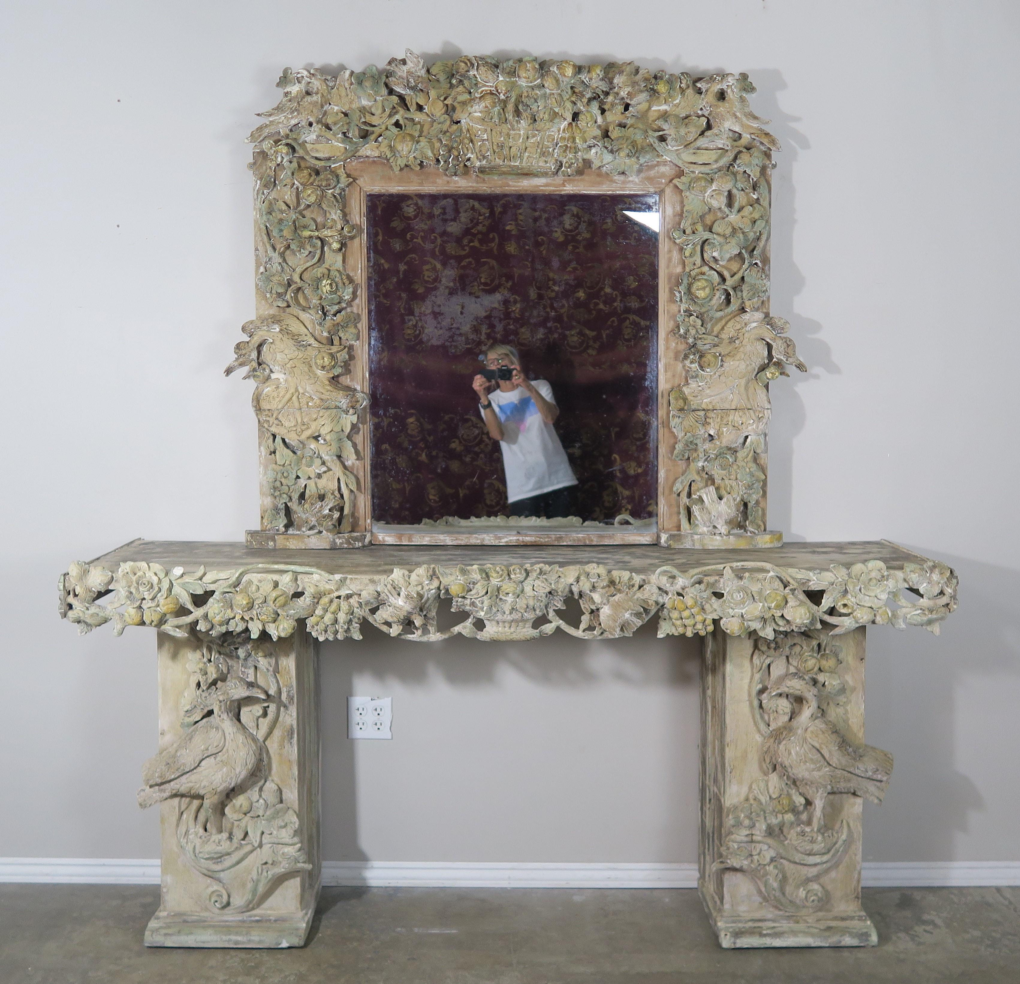 19th century ornately carved Italian Rococo style painted console and mirror depicting baskets of fruit and foliage with beautiful carved birds throughout. The console and mirror are painted is soft hues of faded green and gold on a natural colored