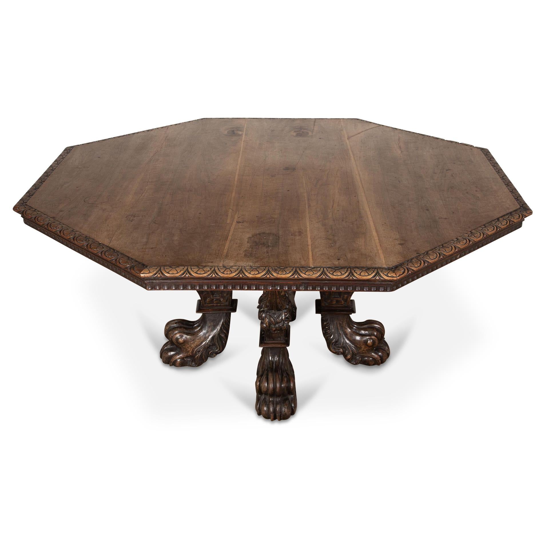 A magnificent mid C19th solid walnut centre/dining table, the octagonal top with a lunette and foliate carved edge above a fluted frieze, on a cruciform base comprised of four shaped shaped volute scrolled supports each carved with overlapping discs
