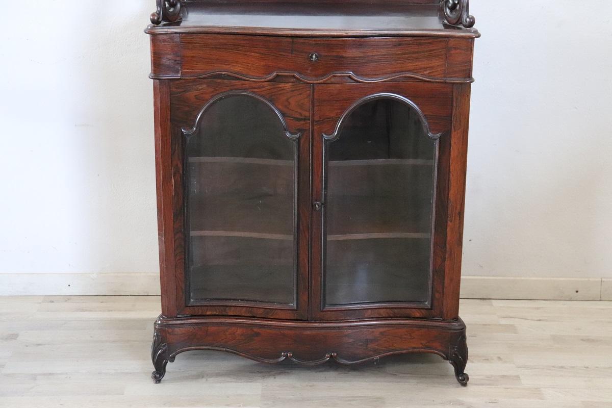 Italian of the period Charles X antique wooden vitrine.  Characterized by a moving and elegant line. In the upper part there is an etagere with two available shelves, supported on the sides by elements finely carved in wood with curls and volutes.