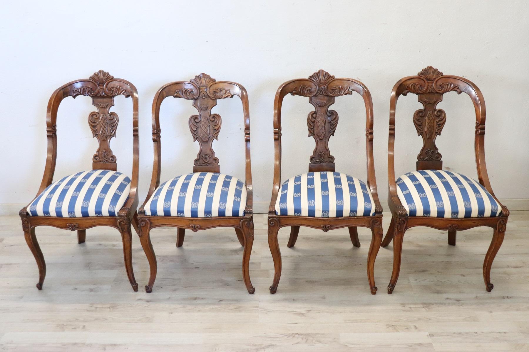 Beautiful 19th century of the period Charles X Italian set of four chairs antique in solid walnut wood. Characterized by an enveloping and refined backrest, embellished with an elaborate decoration hand-carved in walnut wood. The seat is wide and