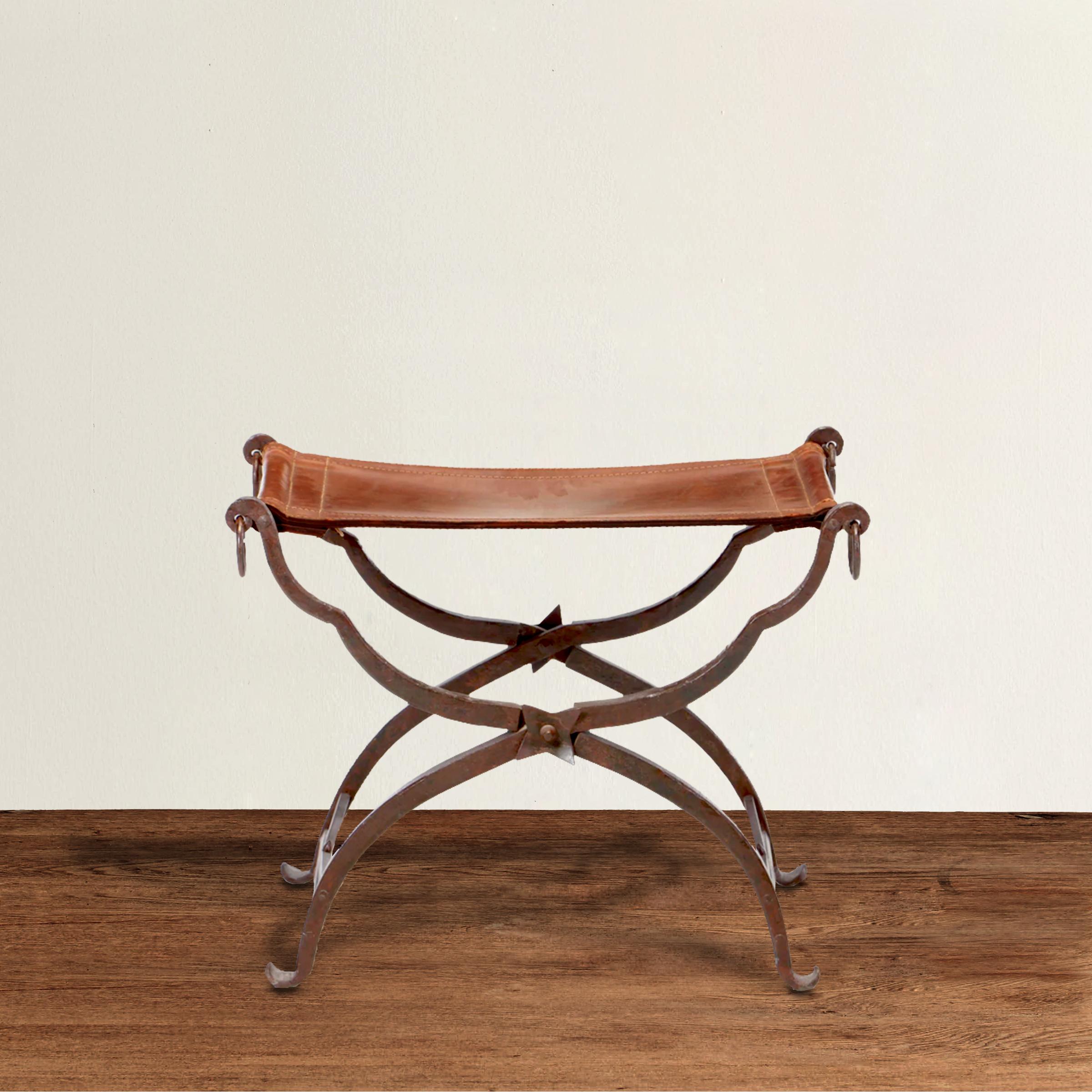 An incredible 19th century Italian wrought iron folding Curule stool with a hand-stitched saddle leather seat, rings on the ends, and decorative stars where the legs cross on both sides. Curule seats were designed by early Romans and was seen as a
