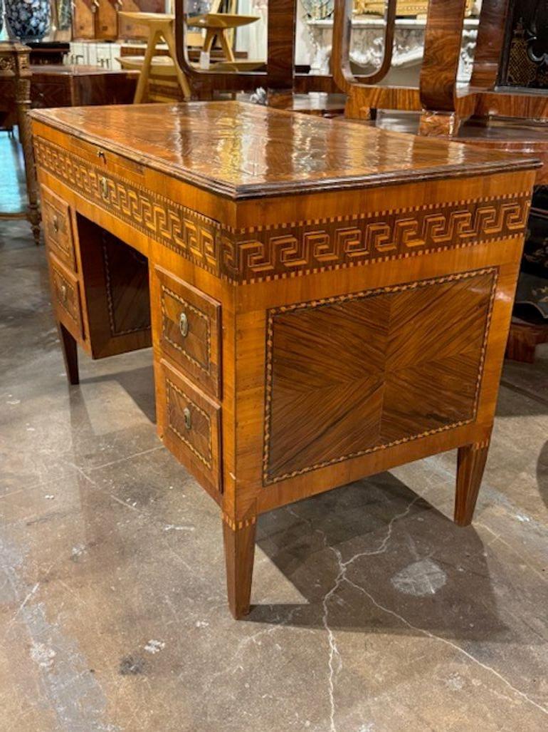 Der italienische Schreibtisch aus dem 19. Jahrhundert mit griechischen Schlüsselintarsien ist ein atemberaubendes Möbelstück, das Eleganz und Raffinesse ausstrahlt. Die schöne Nussbaumoberfläche und das dekorative Design  verleiht jedem Raum einen