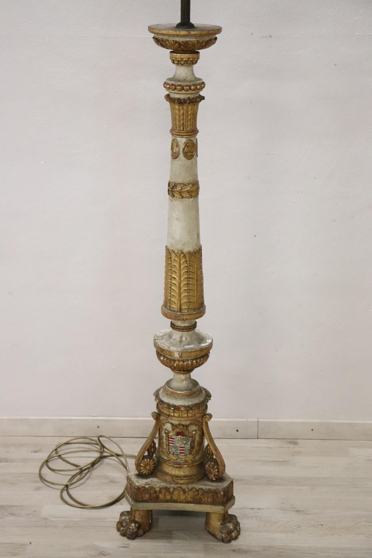 Large carved and gilded wooden floor lamp antique torchère. It has been electrified for modern use. Made with fine woodcarving work, the turned body has many decorative elements and a heraldic crest on the lower part. Beautiful small flattened feet.