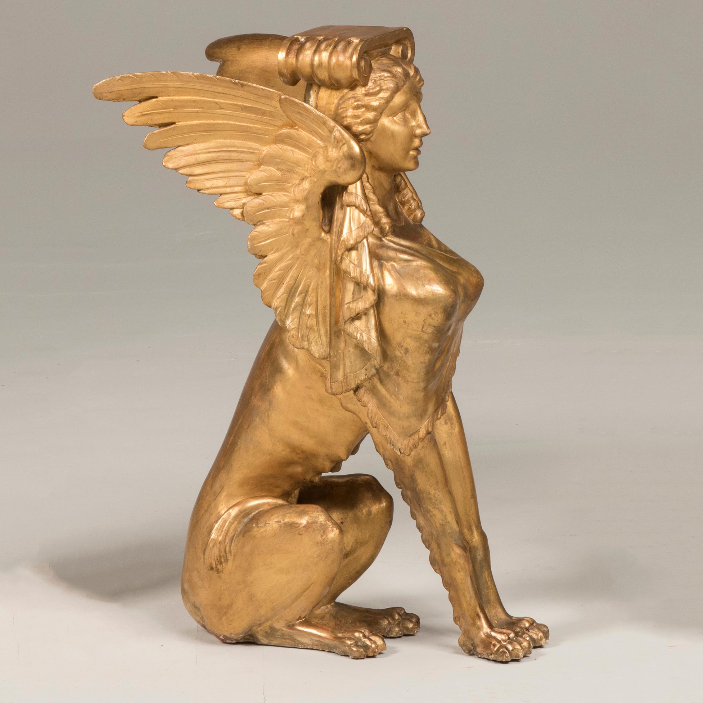 19th century Italian empire period giltwood sphinxes, set of two bases

Two wood gold foil sphinxes with woman head and wings. Originally used as legs for a table, today they can be reinvented as console tables, nightstands, coffee tables or