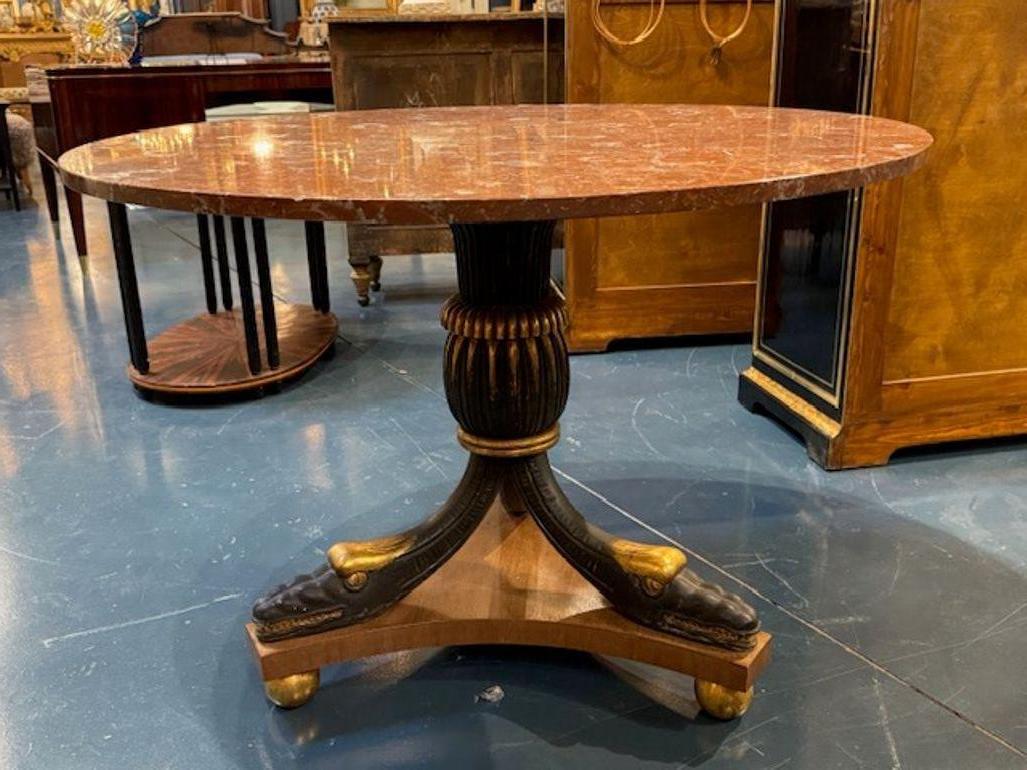 La table de style Empire italien du XIXe siècle avec plateau en marbre est un meuble luxueux et élégant qui respire la sophistication et la grandeur. L'ornementation de style Empire est mise en valeur par l'ébénisterie et la dorure.  Le plateau en