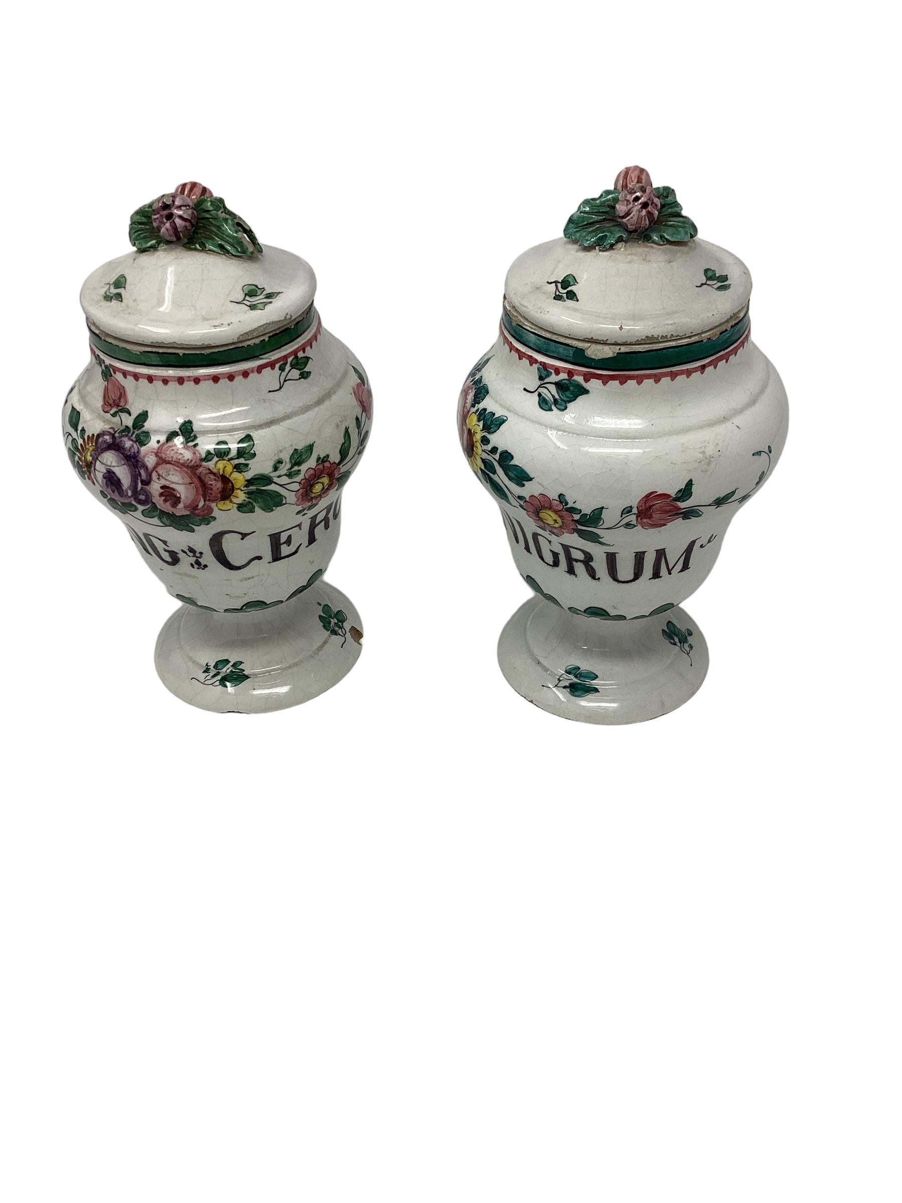 19th Century Italian Faience Floral Decorated Apothecary Jars. Each with applied floral finials. both with latin inscription depicting the type of medicine contained in each jar. One reads 
