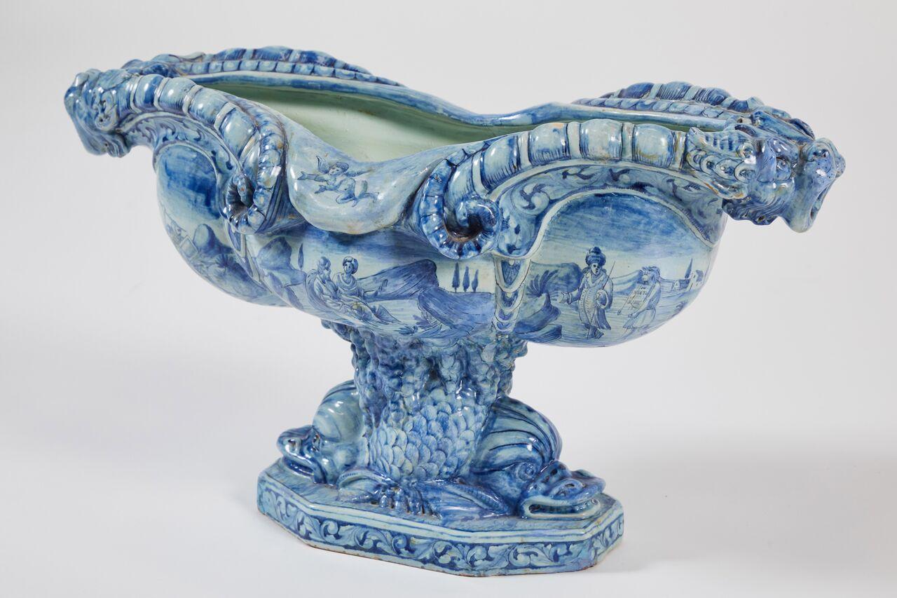 Attractive 19th century Faience jardiniere decorated in shades on blue on a pale blue ground of landscapes with soldiers, shepherds and putti, mountains, and trees. Ornate handles at either end formed as open-mouthed gargoyles with horns forming the