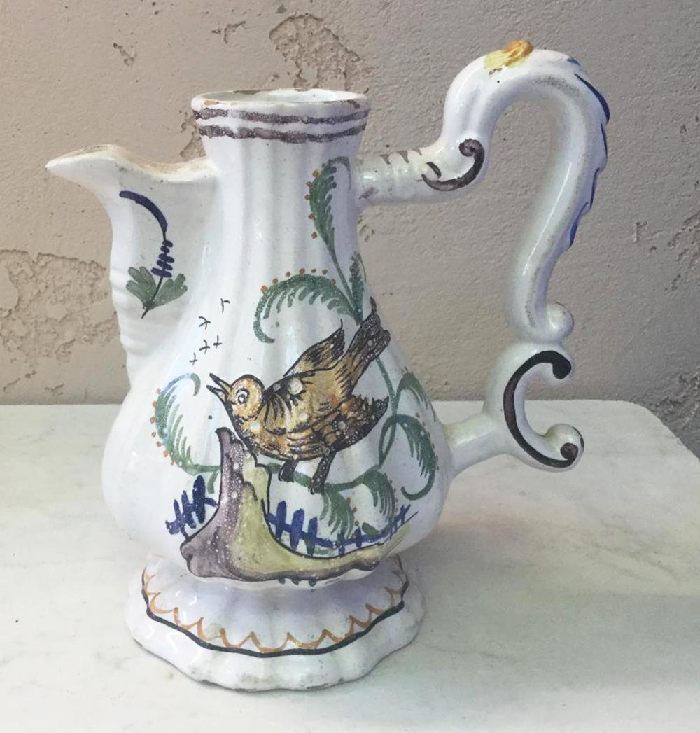 19th century Italian faience pitcher decorated with bird on a fence and a tree on the other side.