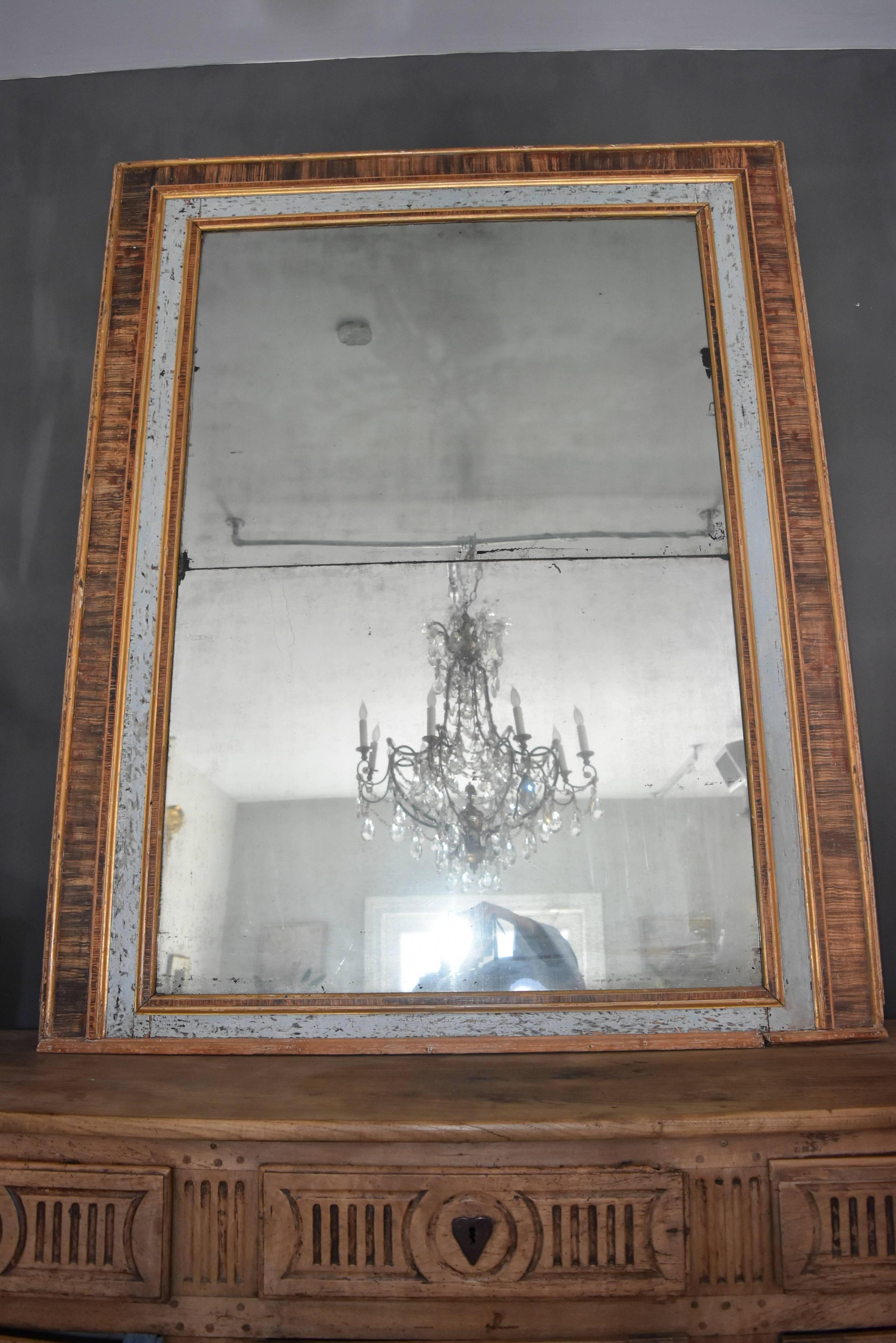 This Italian mirror is a beautiful pale blue with faux marble paint that looks like a fine wood grain. It's mirror is a two part original glass which was typical during the earlier times when they couldn't make the glass in large sizes without