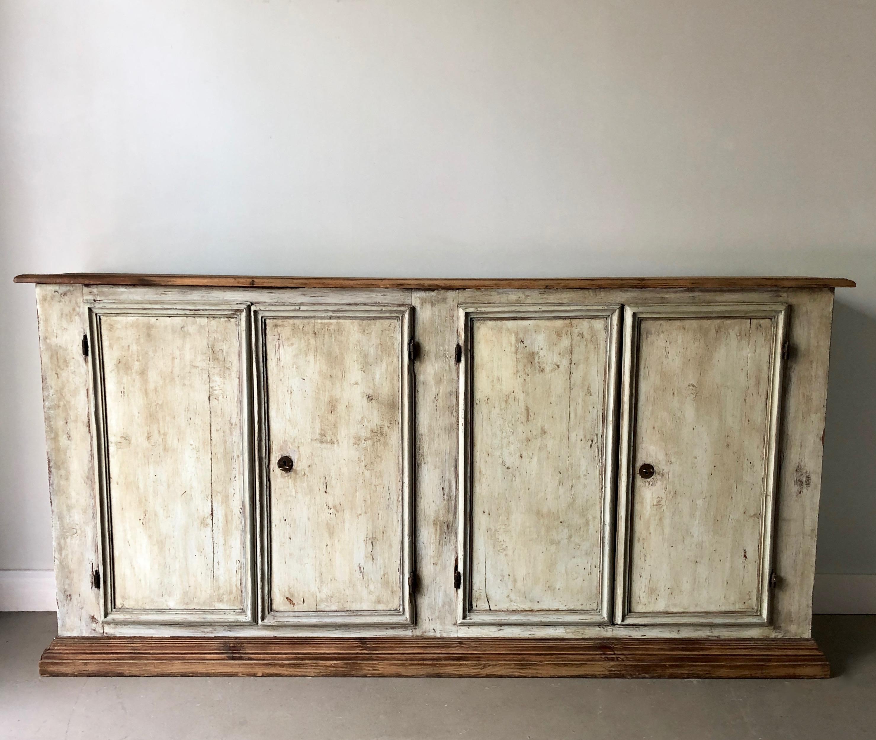 A large Italian painted sideboard with four paneled dubble doors, natural patinated wooden top and base. Original iron hinges.
Old aged broken locks replaced with keys.