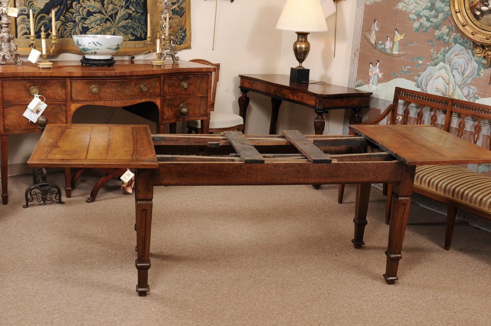 The walnut Italian refractory table with fruitwood top and 2 pullout / pull-out extension leaves. The legs made out of oak with tapered and carved fluting detail. 

The total length with leaves extended out is 115