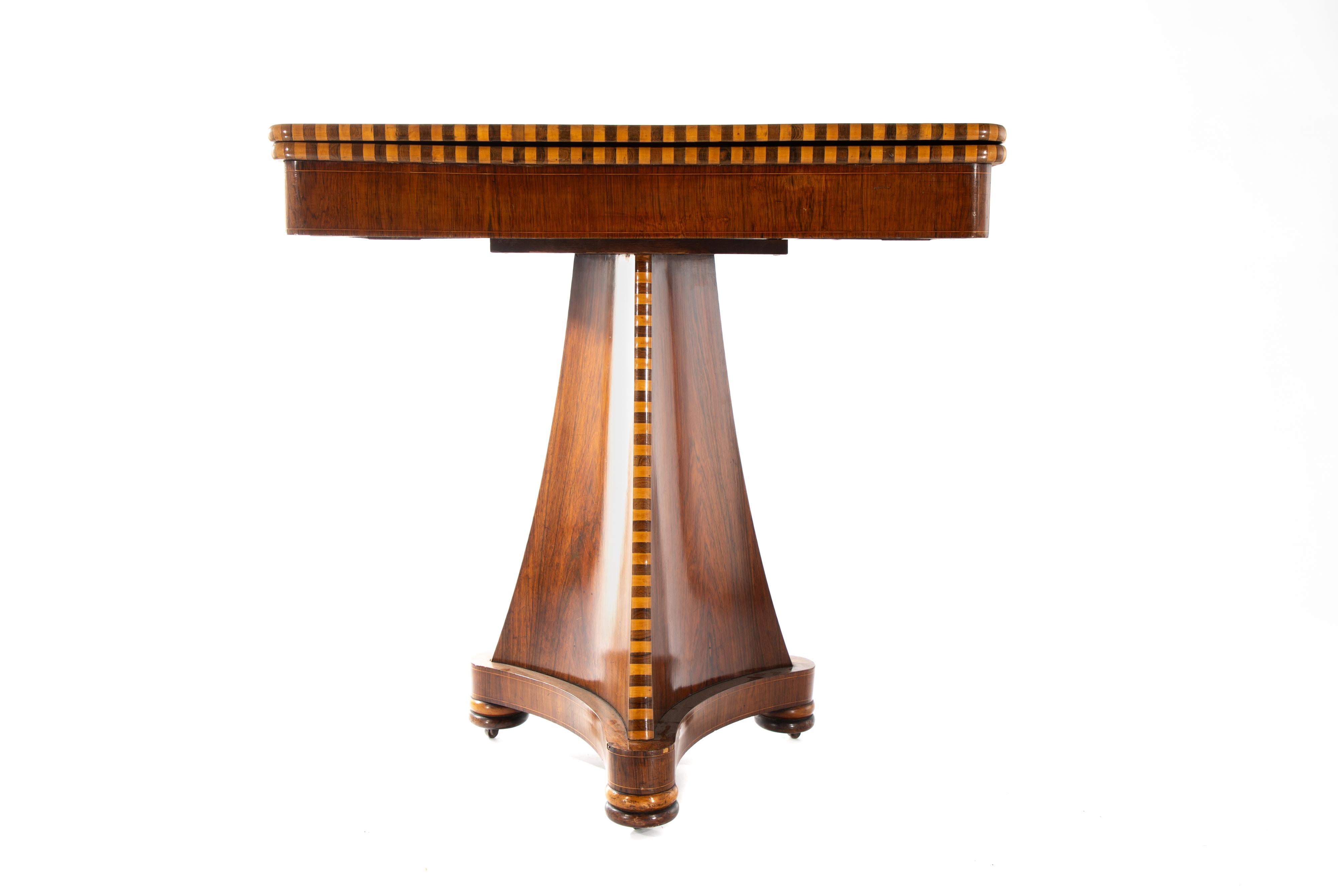 19th century Italian Empire style game table.  
Rosewood and boxwood veneers, marquetry sunburst in center of table and striping along three exposed edges.  
Opens to expose a circular gaming surface of leather with gilt embossing.
On a triangular