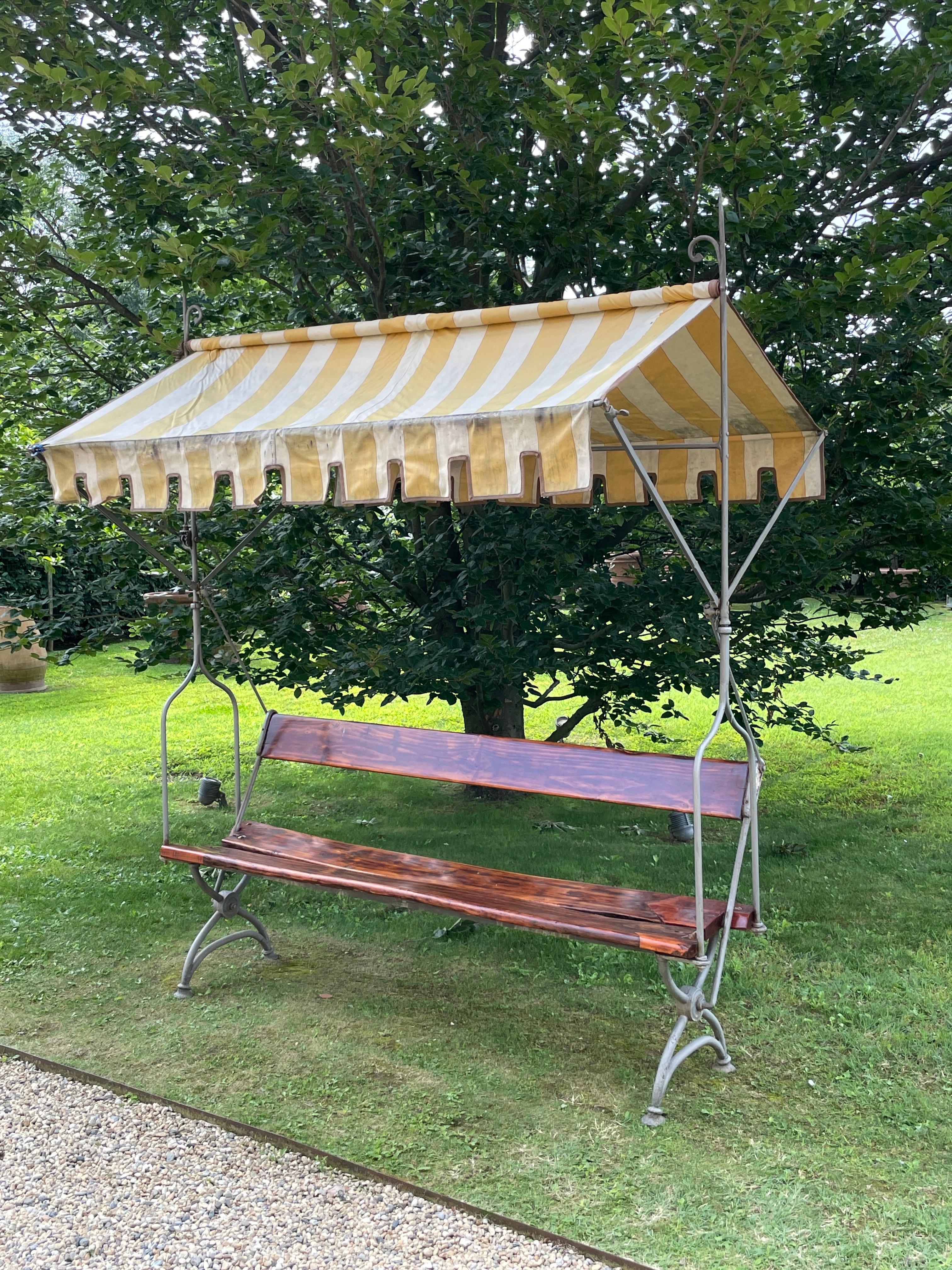 Banc de jardin italien du 19ème siècle en bois et fer forgé avec auvent en tissu

Ce rare banc de jardin a été fabriqué en Italie au 19e siècle.
La structure est en fer forgé. Le siège est constitué de deux planches de bois. Le dossier, incliné pour