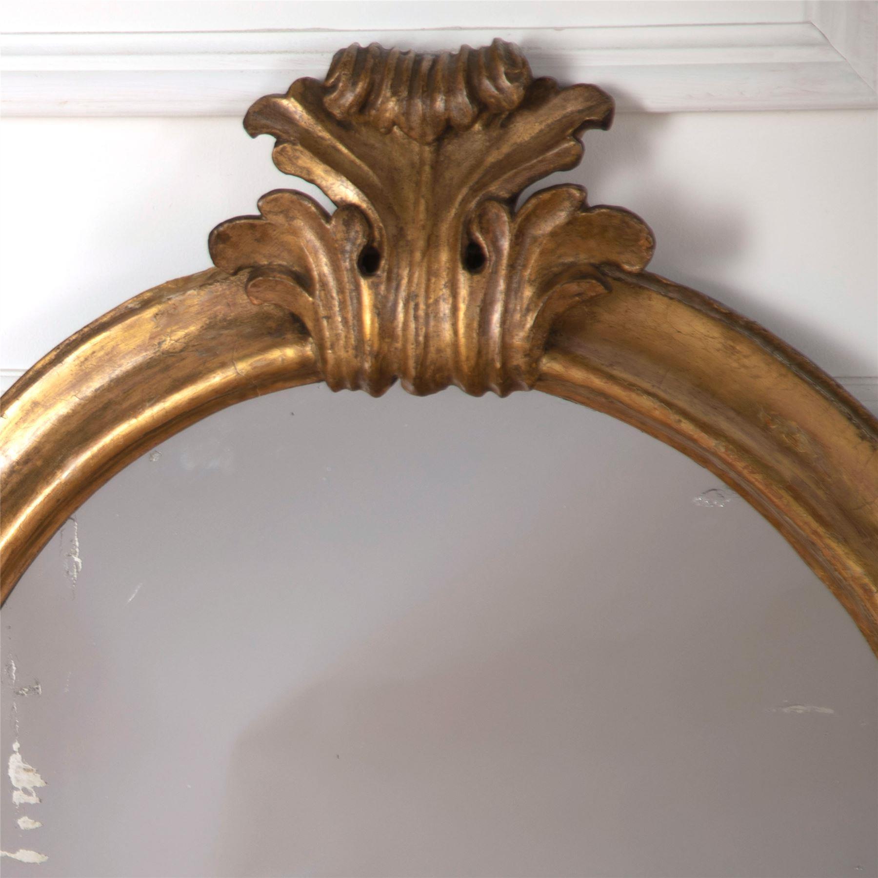 Une paire de miroirs muraux italiens du 19ème siècle, ovales et dorés, avec une belle crête centrale et des plaques originales.