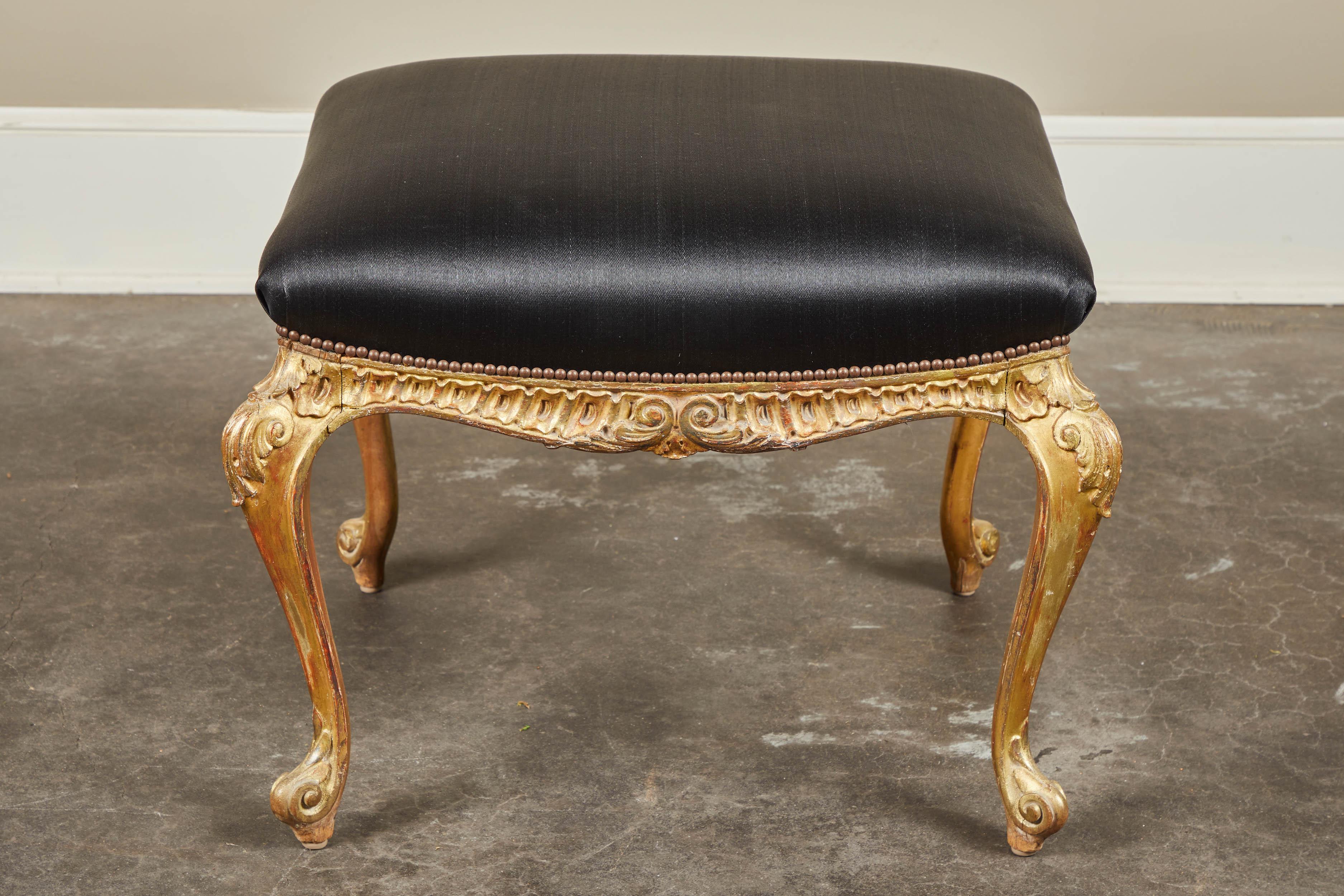 A 19th century Italian gilt and paint footstool with carved fleur de lieu and black horsehair upholstery.