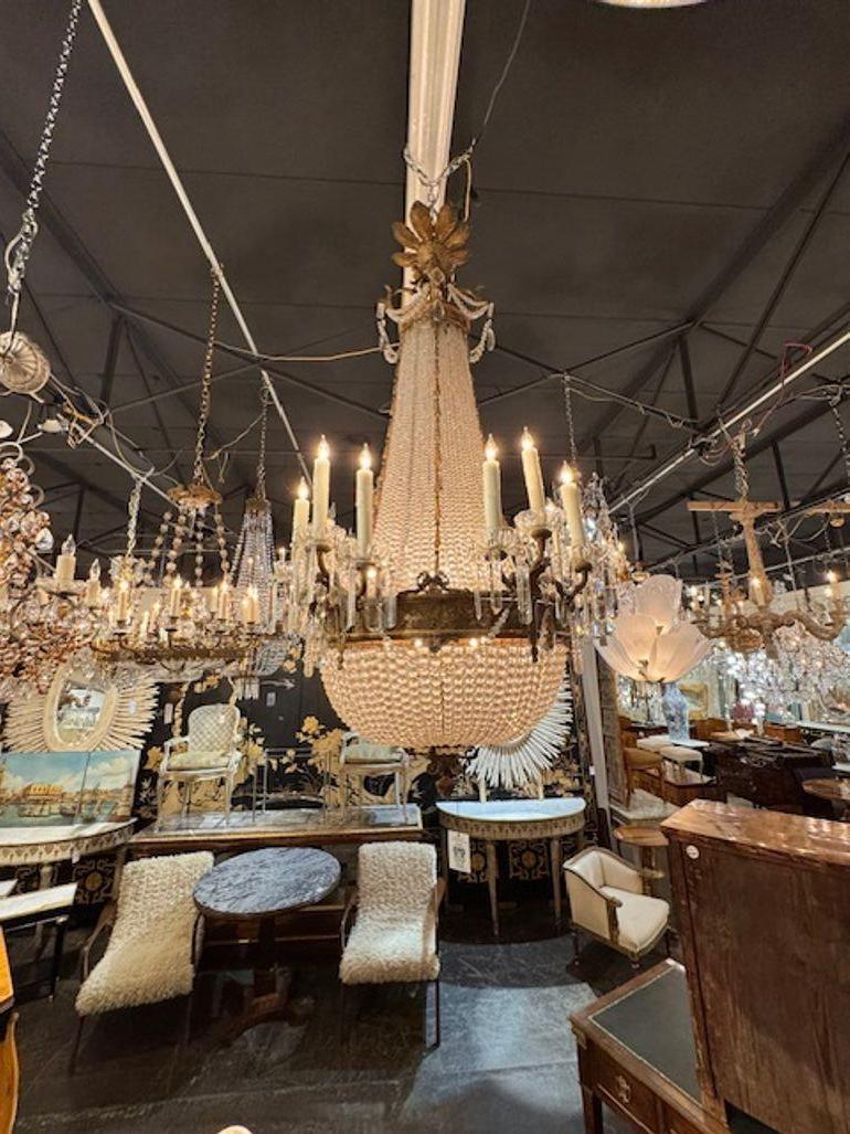 Questo lampadario a cesto in bronzo dorato e cristallo del XIX secolo è un pezzo straordinario che combina perfettamente eleganza e raffinatezza. L'intricata struttura in bronzo dorato è ornata da scintillanti accenti di cristallo, creando un design