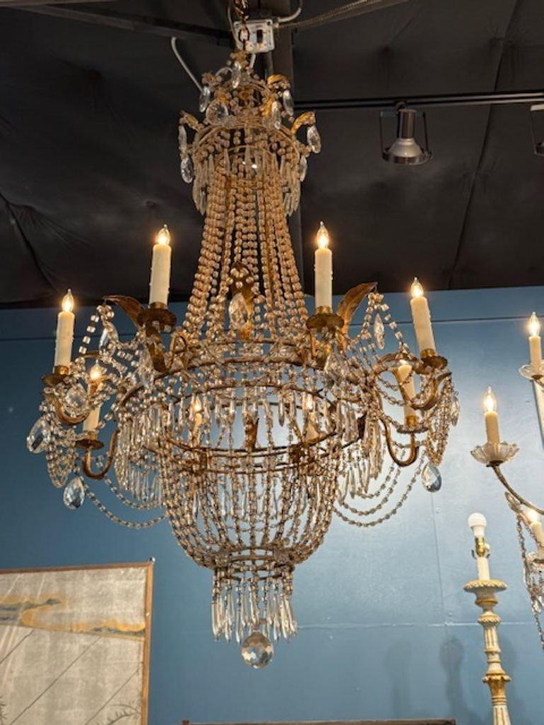 This 19th-century Italian Empire style gilt tole and crystal basket chandelier exudes a touch of elegance and sophistication. The intricate design features a beautiful combination of gilded tole and sparkling crystal, making it a stunning