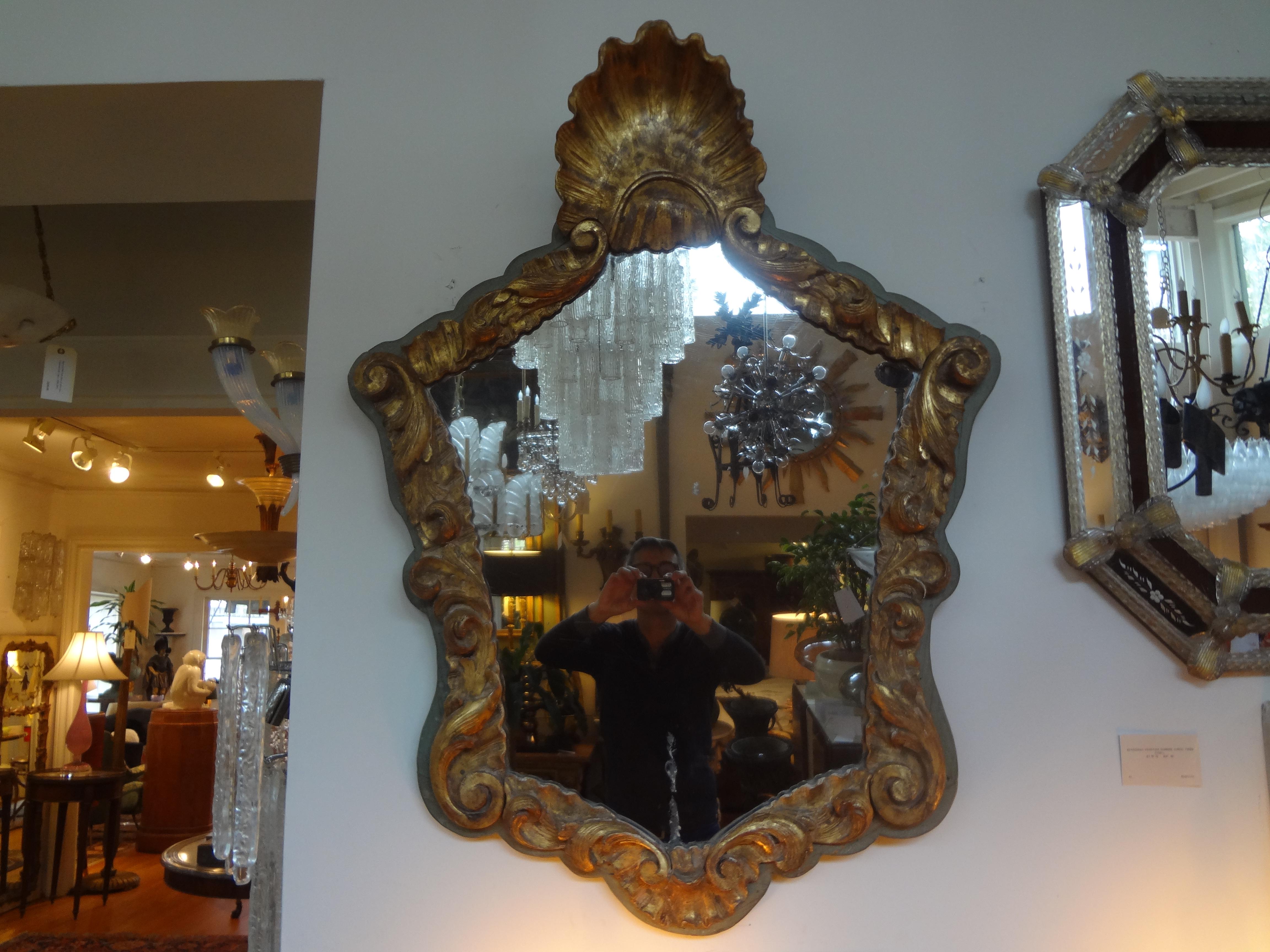 Stunning early 19th century Italian giltwood mirror with shell design. Well detailed with fabulous time worn patina to the gilt. This Italian giltwood mirror would work well in a variety of interiors and would be perfect in a powder bath.
