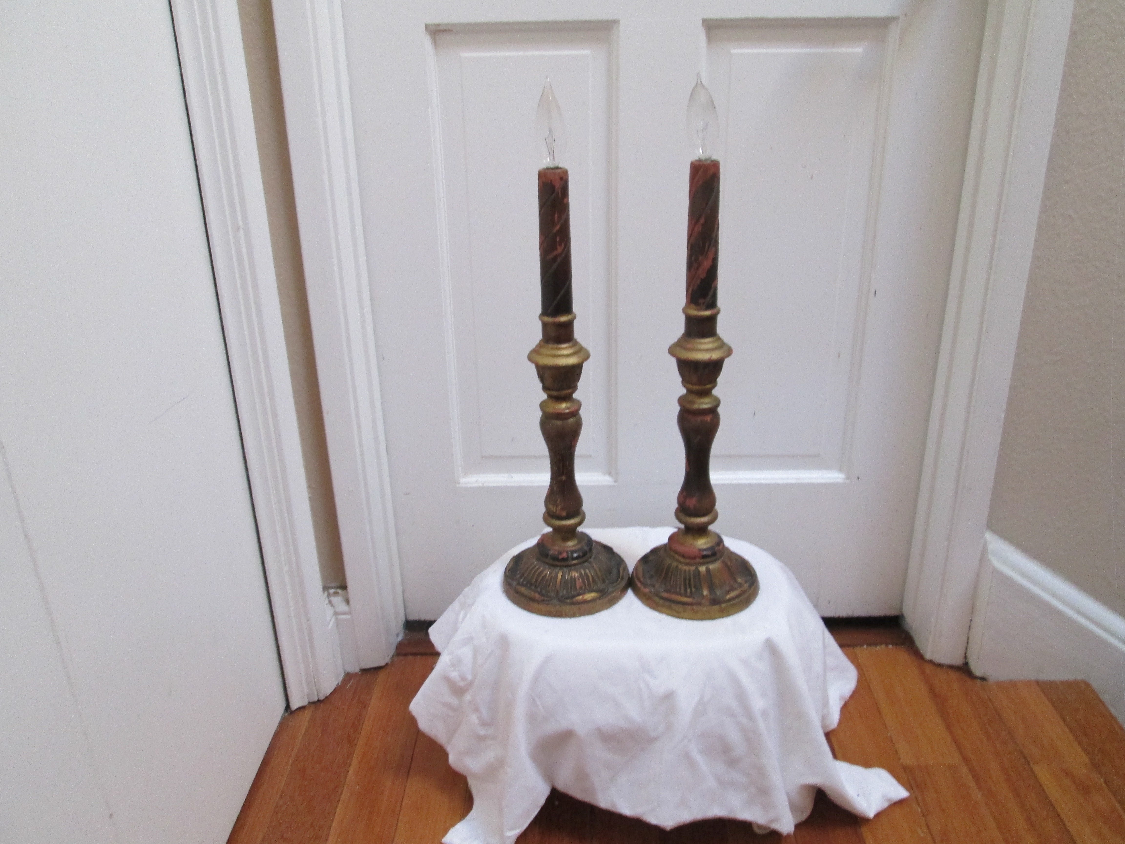 Authenticity and artistry are the calling cards of this pair of 19th century wood gilt candlestick lamp conversions. This is a pair of Italian lead weighted gilt wood antique candlestick lamps. The gilt, burgundy and tan are worn and elegant with a