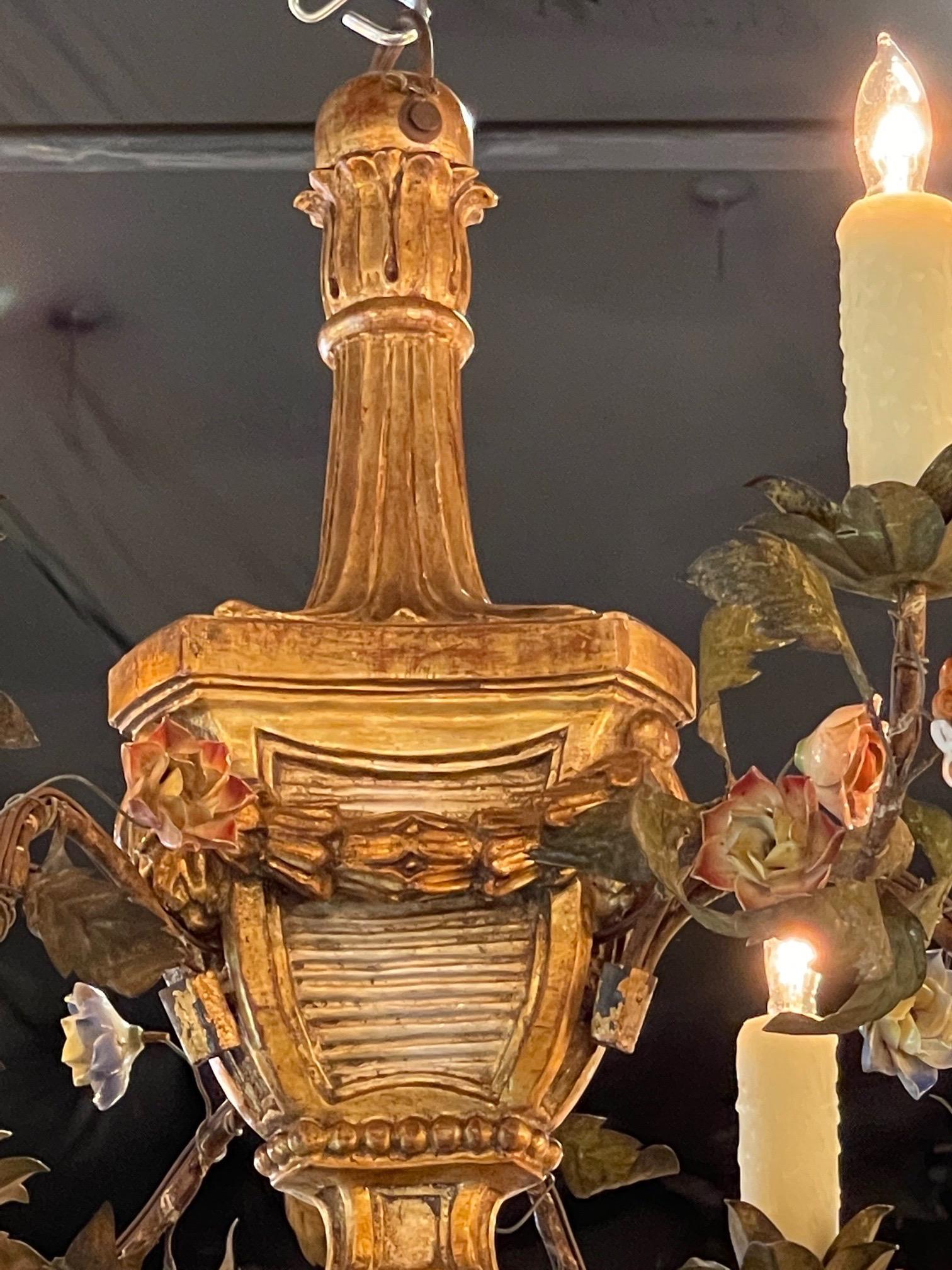 Lovely 19th century carved Italian giltwood and iron chandelier with porcelain flowers of pink, white and blue. The fixture has 6 lights and a beautifully carved base as well. Very unique!!