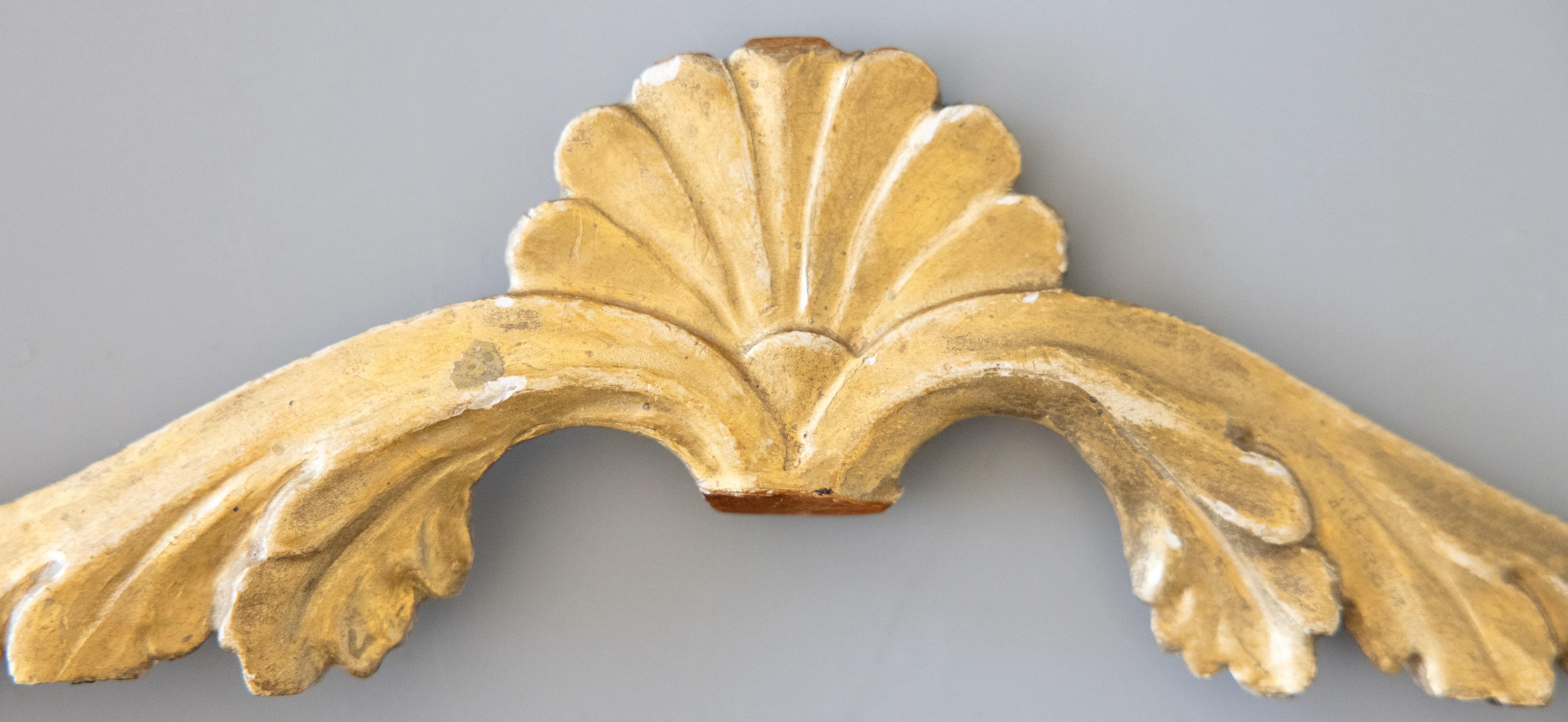 A gorgeous antique 19th-Century Italian gilt wood pediment / architectural fragment / wall swag / hanging wall ornament. This stunning architectural element has a lovely shell centerpiece with carved scrolling leaves and retains the beautiful