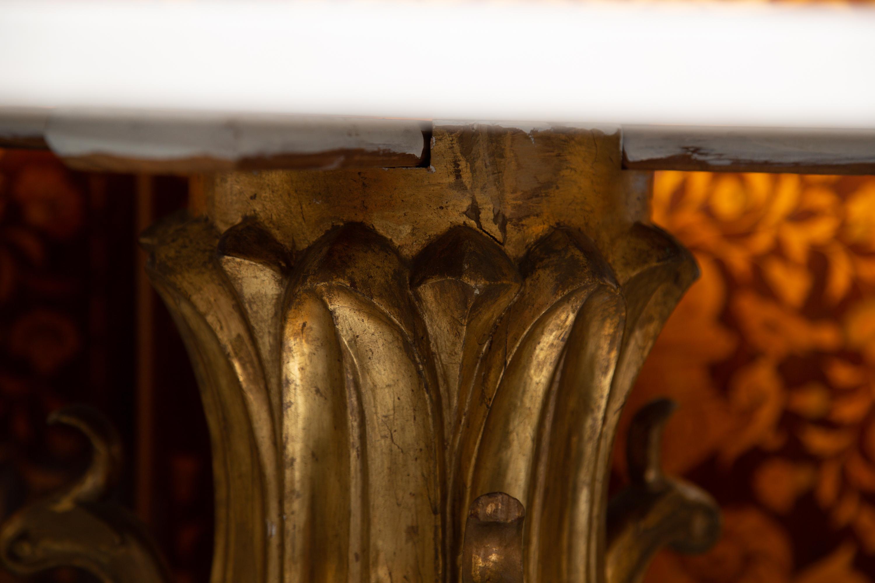 This is a very sophisticated Italian giltwood center table with a circular limestone top supported by a carved pedestal depicting stylized birds with winged feet situated on a shaped platform. 19th century.