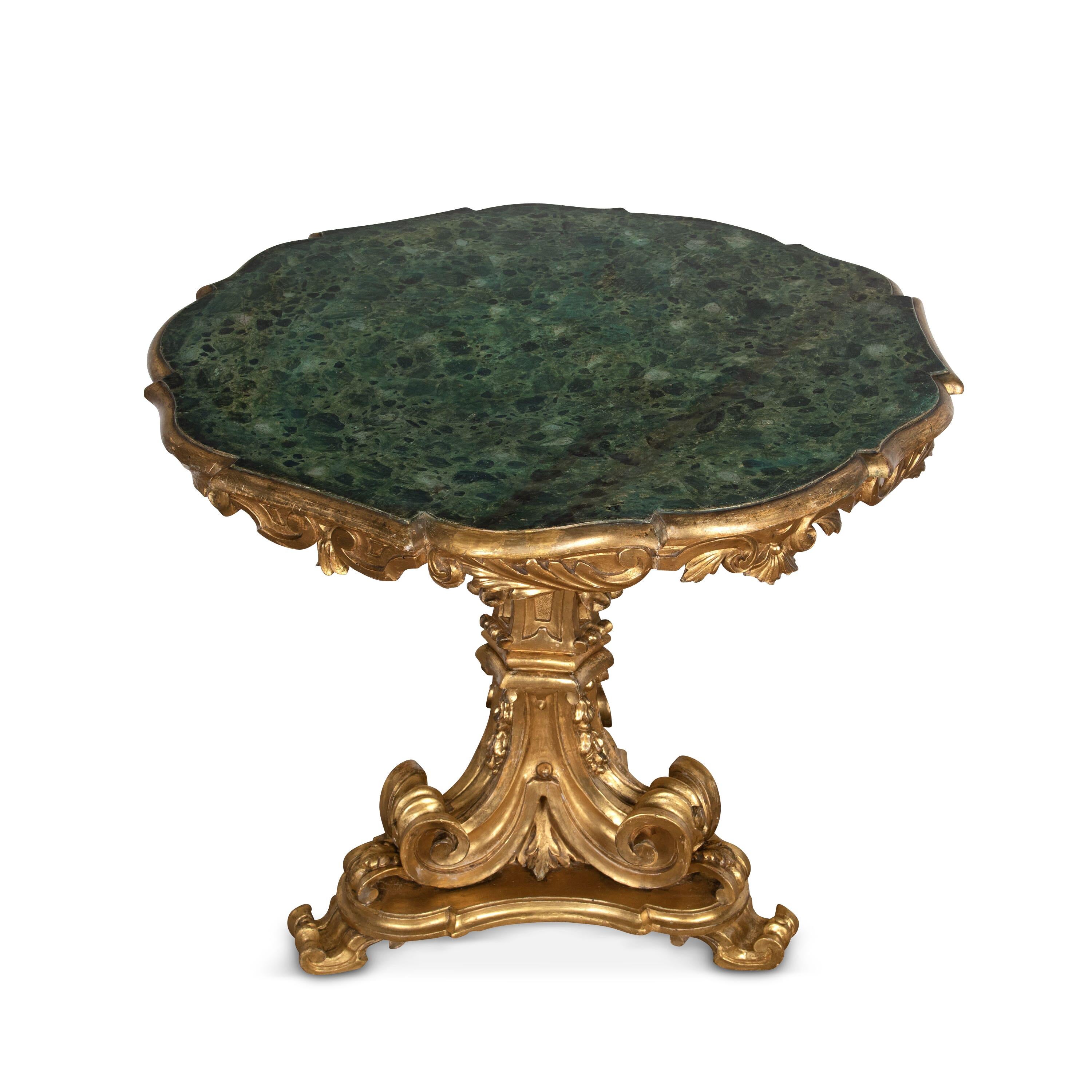 A stylish early 19th century Italian centre table. The simulated marble top with shaped moulded edge and acanthus carved frieze, raised on a shapely giltwood triform base with exaggerated scrolls, foliate carving, and terminating in further scroll