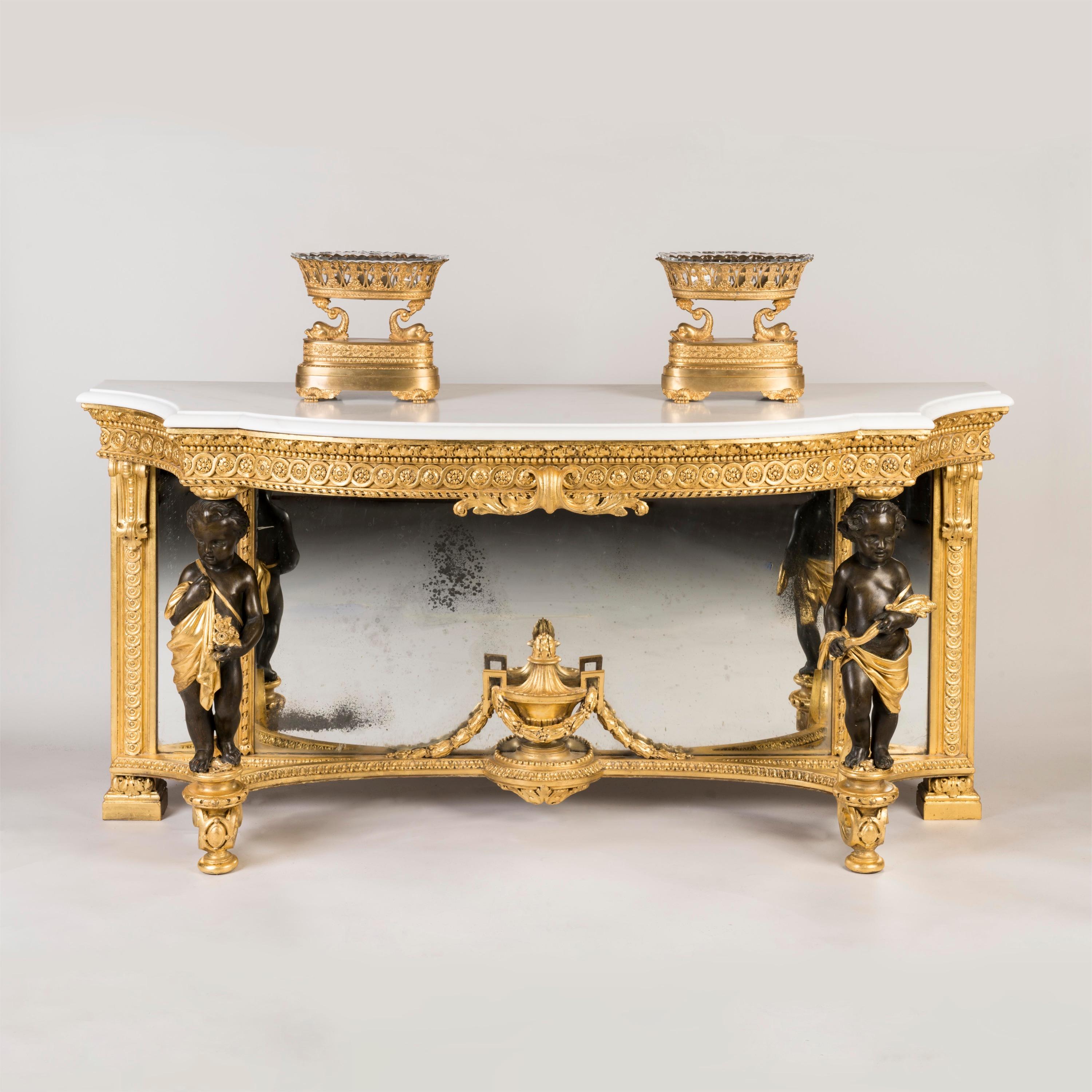 A good console table in the Louis XVI Manner

Gilt wood, with decorated highlights; of arc-en-arbalette form, the white Carrara platform having a thumbnail moulded edge, being supported by a framework of two draped putti, one carrying a posy of