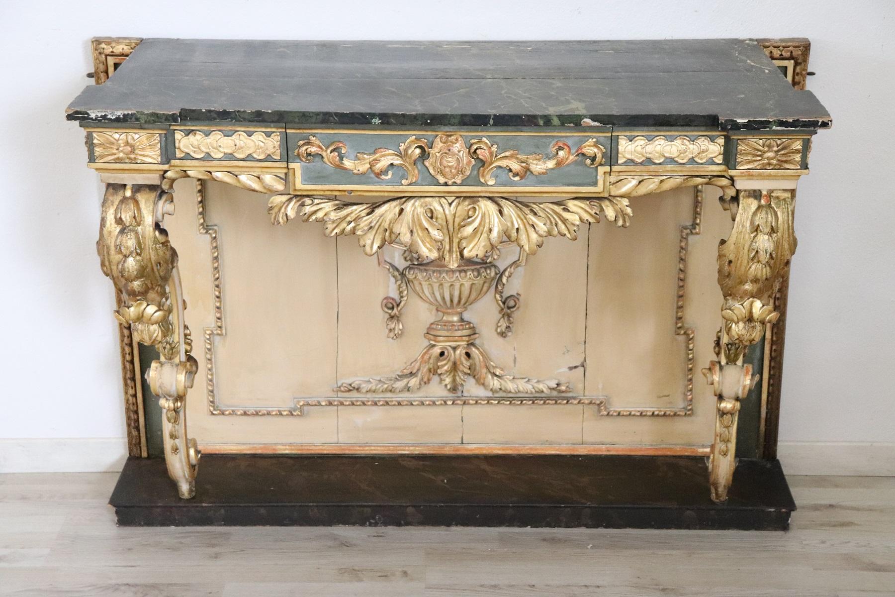 Italian antique console table, 1840. Characterized by precious lacquered and gilded. The top is made of a faux marble painted decoration. The wood is finely decorated with carving with moved front legs. Many decorative elements of classic taste look