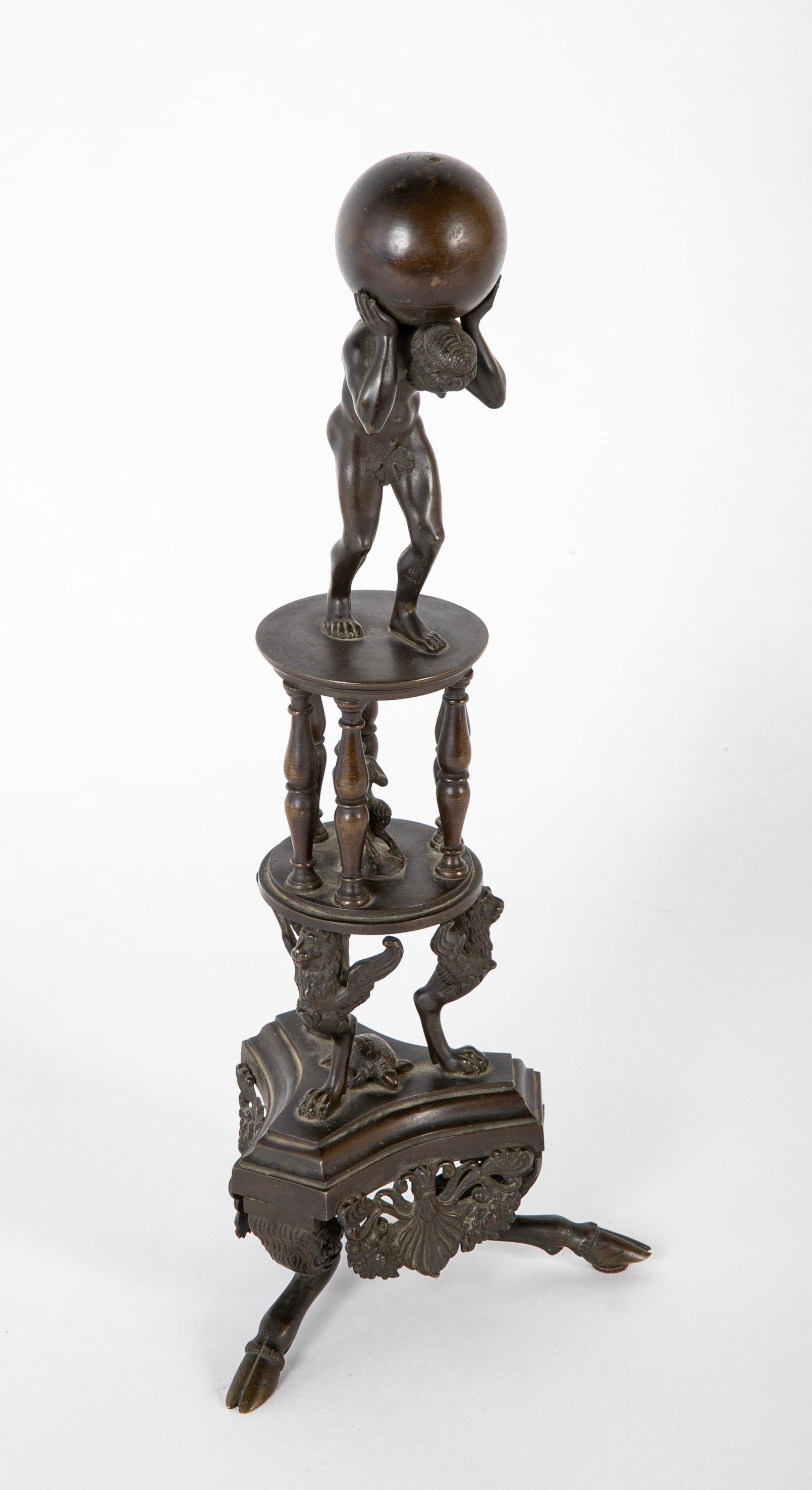 Italian Grand Tour bronze in the Renaissance style of Atlas on an elaborate tripod base ending in hoof feet. The Greek god Atlas is is depicted naked on top holding the world upon his shoulders, below in a columned arcade sits Pan with his flute. On