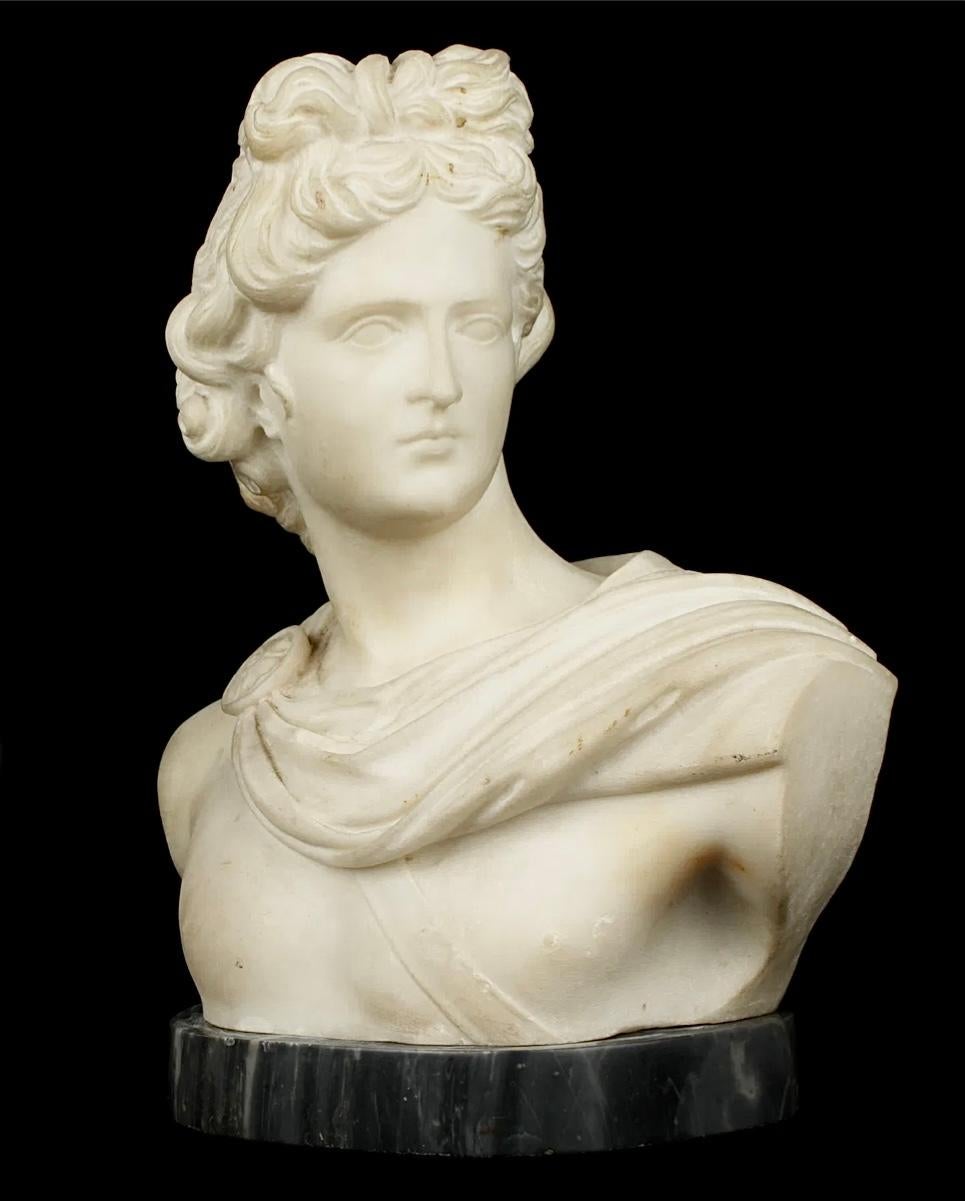 Busto di Apollo in marmo bianco scolpito del Grand Tour italiano del XIX secolo, fissato su un basamento in marmo variegato, senza firma visibile. Apollo era il dio greco del sole, della musica, della poesia e della filosofia con caratteristiche