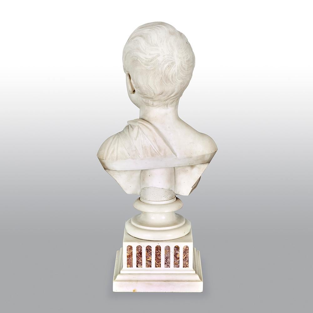 An 19th century Italian grand tour Carrara marble bust of a young boy, In classical taste, his head slightly turned, on a square sienna and Carrara marble socle base.