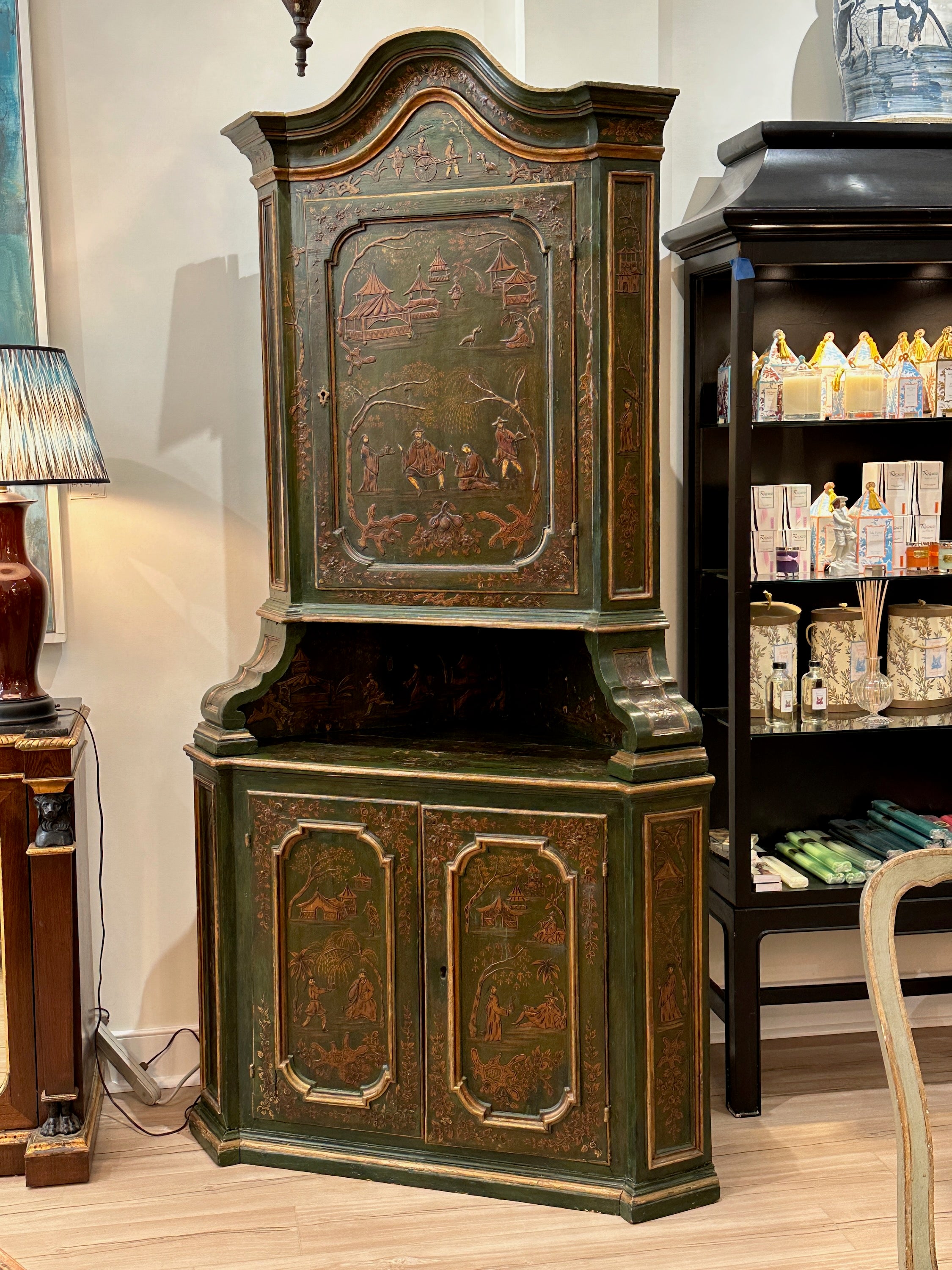 A large and imposing late 19th C. Italian green chinoiserie decorated two-part corner cabinet. The upper portion displaying an elaborately carved curved pediment above a single door. The lower portion with two recessed panel doors opening to storage