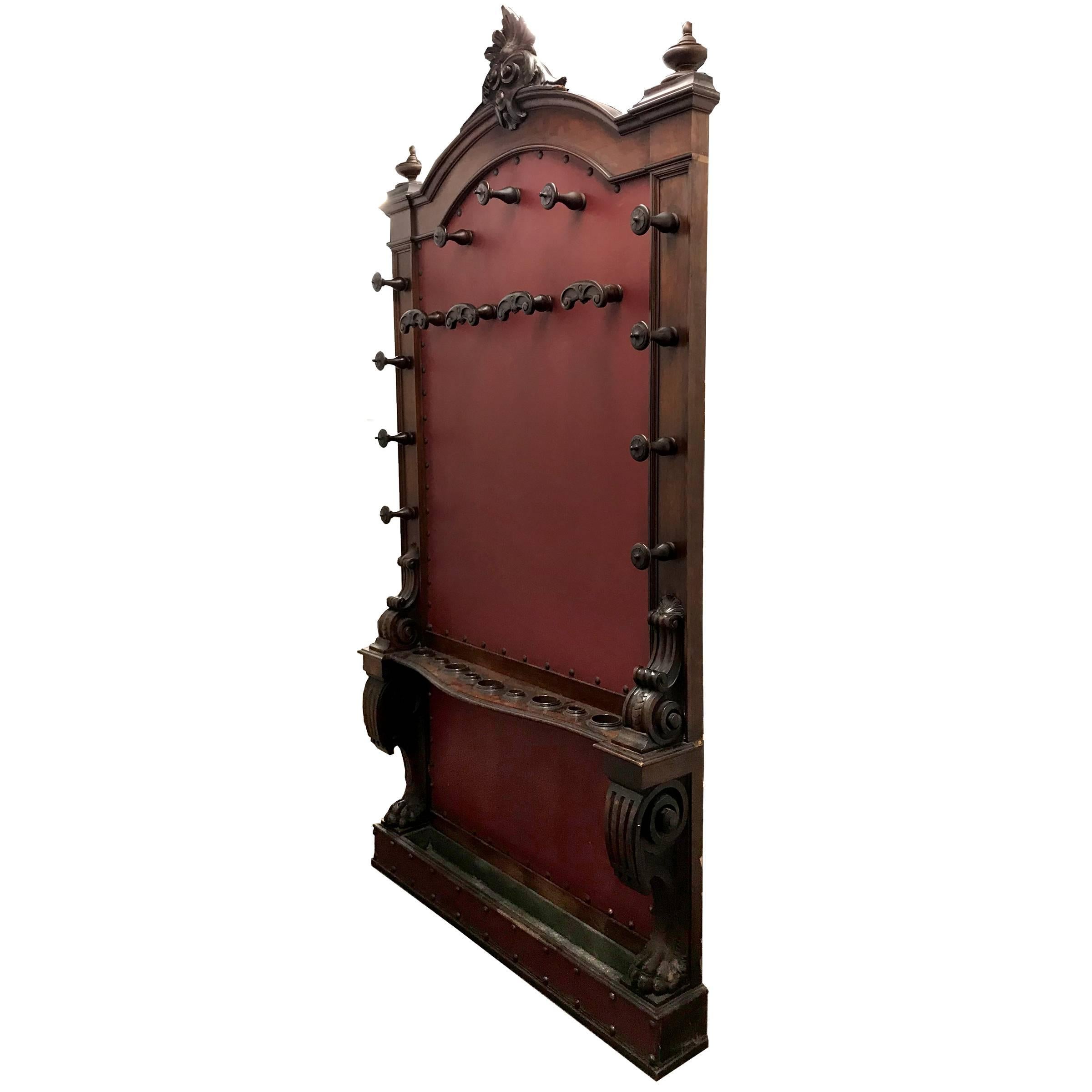 An impressive 19th century Italian walnut hall tree with four coat hooks, eleven hat hooks, and nine spots for umbrellas and walking sticks. There is a zinc lined tray at the bottom for holding water from the umbrellas. The umbrella rack is