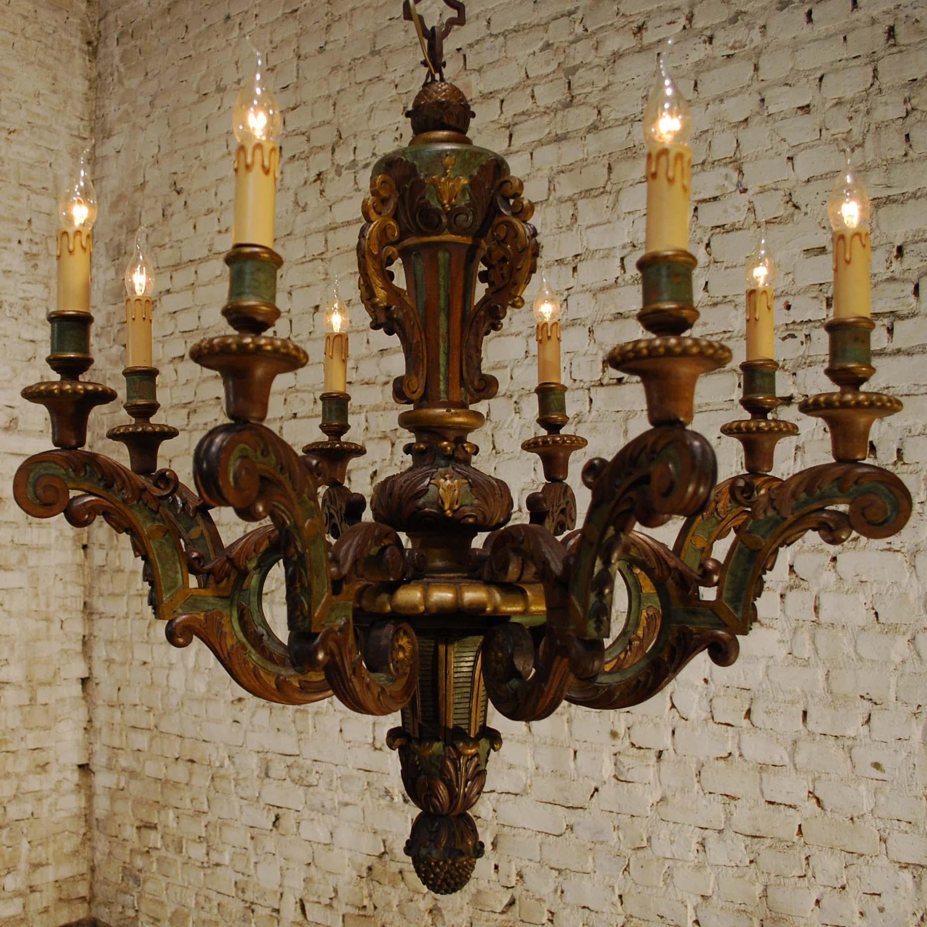 This elegant antique polychrome carved wood chandelier was made in Italy during the late 1800s. It is hand-carved in solid walnut and beechwood. Carved scrolls and a acanthus leaves adorn the body and arms. Together with the polychrome this is a