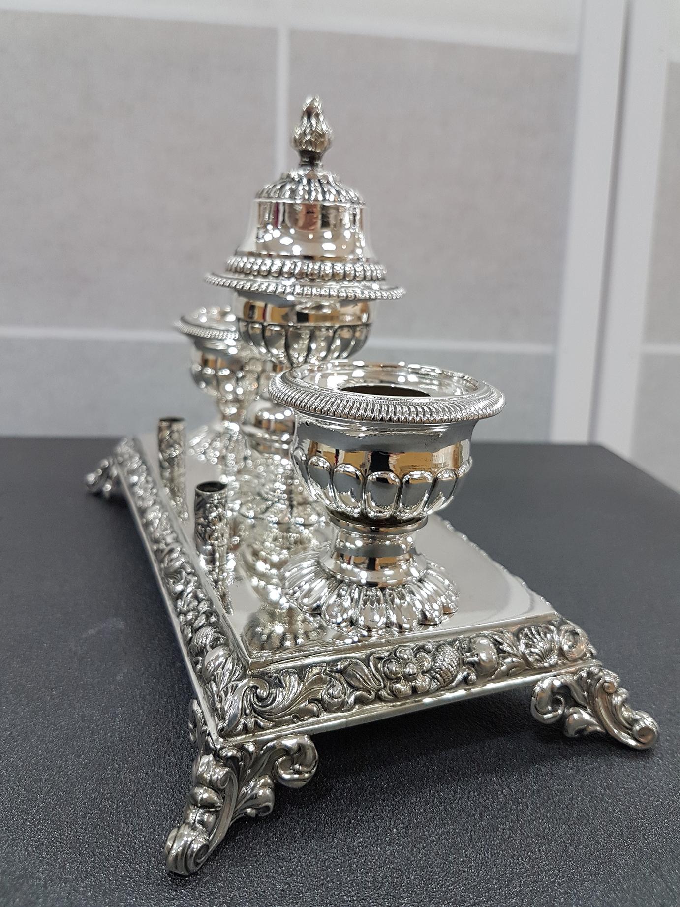 Silver 800 rectangular inkwell on feet in Baroque style characterized by embossed and chiselled shells and swirls.
At the centre of the inkwell a bell is positioned while on the sides there is the talc powder holder and candleholder.
330