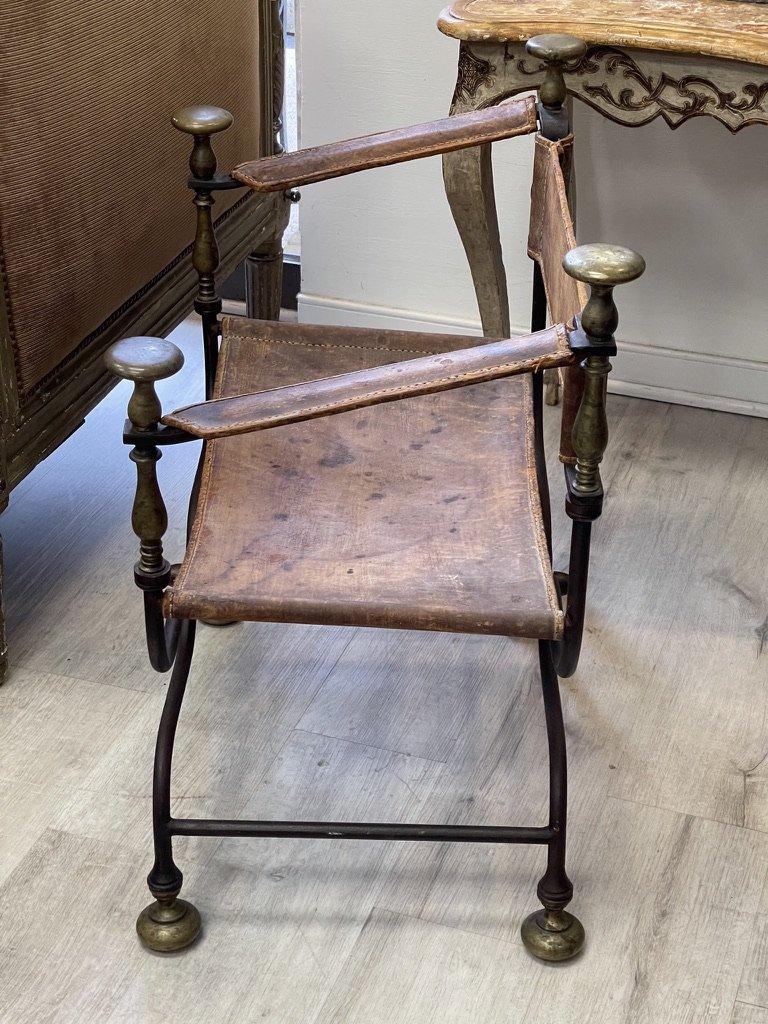 19th century Italian iron, bronze, and leather Savonarola or Dante chair also known as a Curule chair. Featuring a scissor form iron frame that folds in a Campaign style with brass-mounted finials and feet. The seat, back, and arms are upholstered