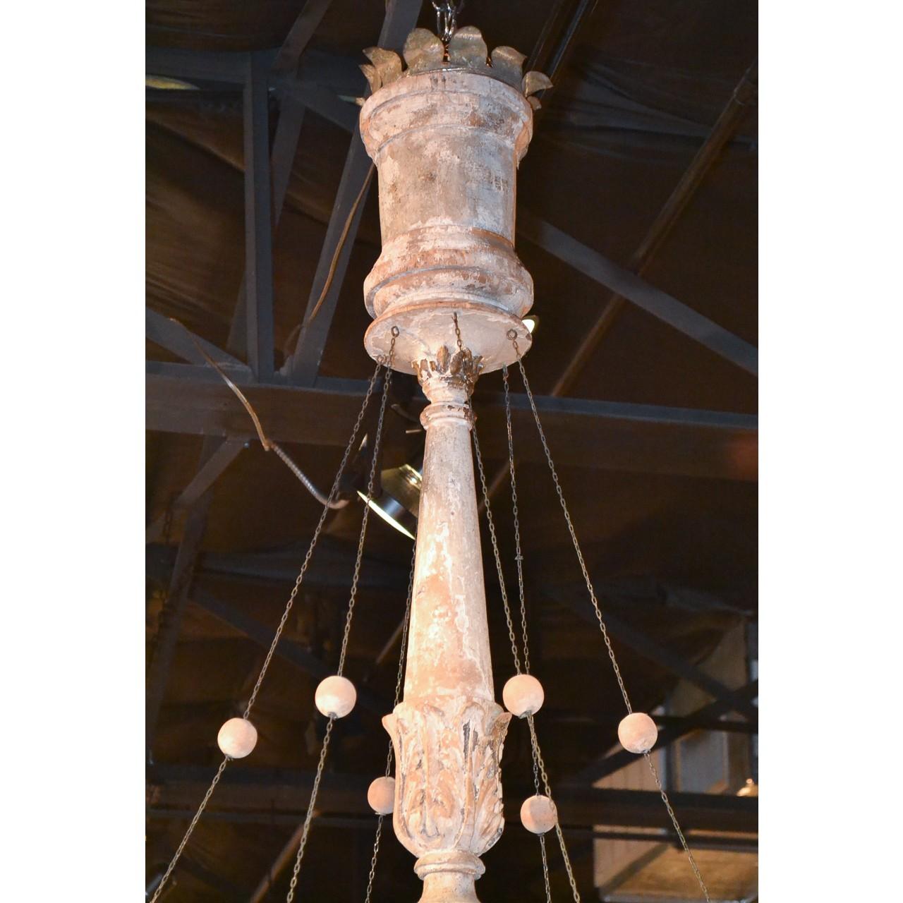 Splendid large-scale mid-19th century Italian iron and painted wood chandelier. The turned, shaped, and hand-carved stem surmounted with six double-loop iron branches holding carved candle cups. Wonderfully accented with strands of wood
