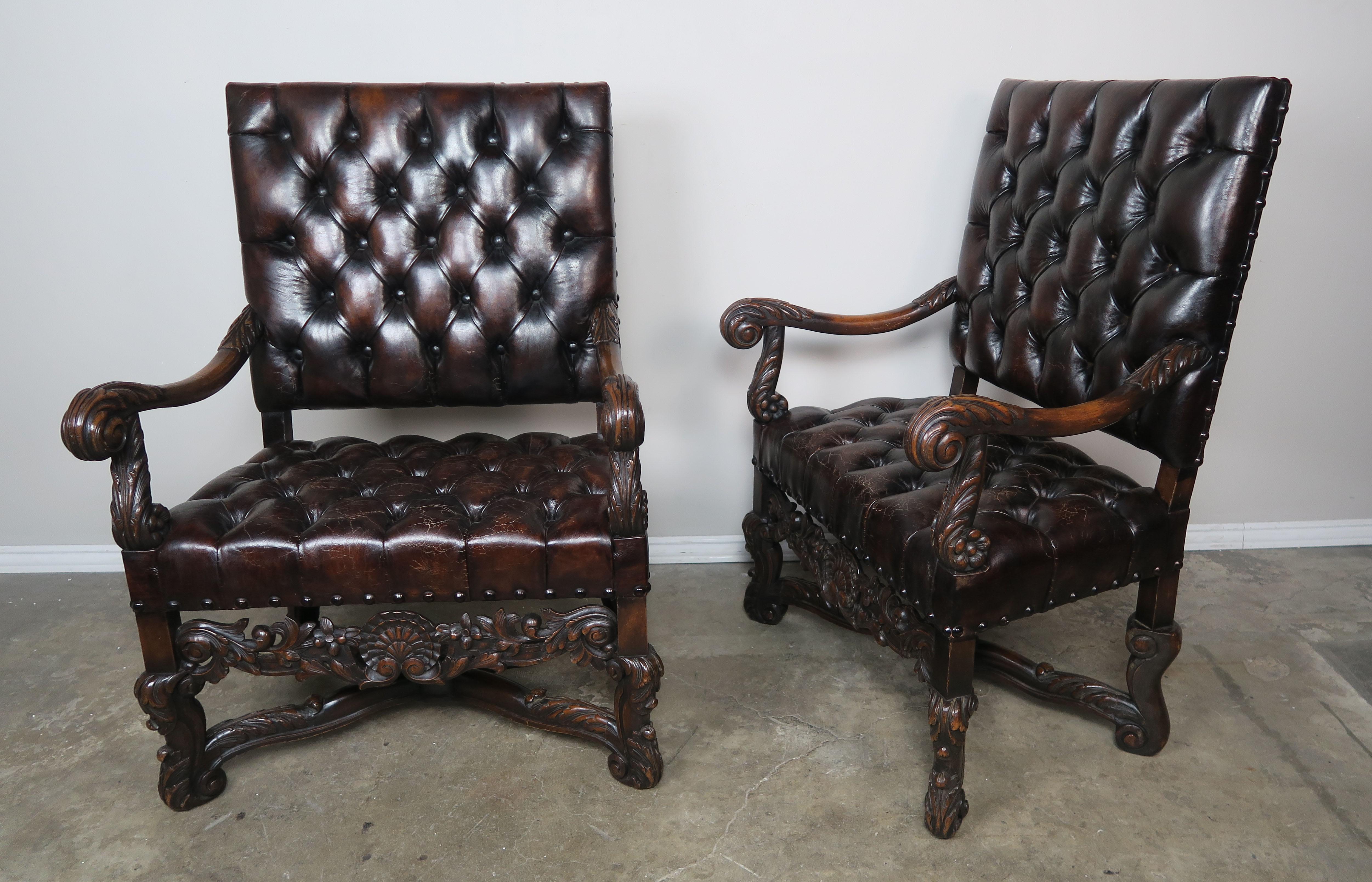Pair of handsome 19th century walnut carved Italian armchairs upholstered in tufted leather with nailhead trim detail. Beautiful carved details throughout including a shell motif flanked by swirling acanthus leaves. The chairs stand on four carved
