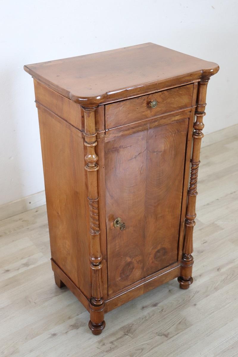 Lovely antique Italian nightstand of the period Louis Philippe, 19th century in solid walnut wood. The nightstand very refined linear and elegant with on the front two decorative turned columns. On the front one-drawer and one-door, internally