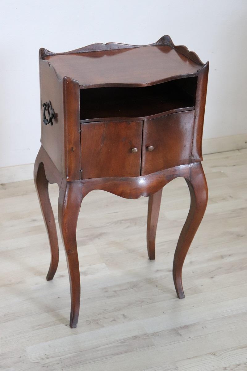 Lovely antique Italian nightstand late 19th century in solid walnut wood. Characterized by a moving line reminiscent of the Louis XV style, slender and arched legs, two doors on the front with a practical internal compartment. Perfect for the