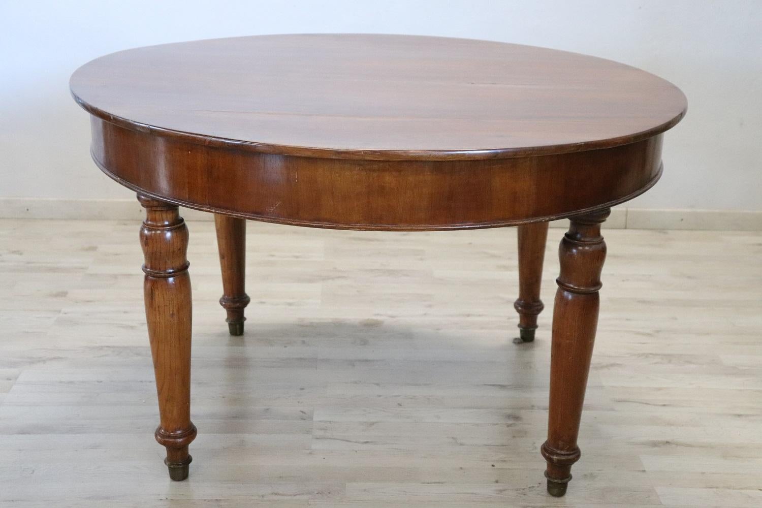 Beautiful important antique round dining room table, 1840s in solid walnut wood. This table is perfect for a dining room, it extends into the center becoming a large table that can accommodate many people. The four legs are elegant and slender. The