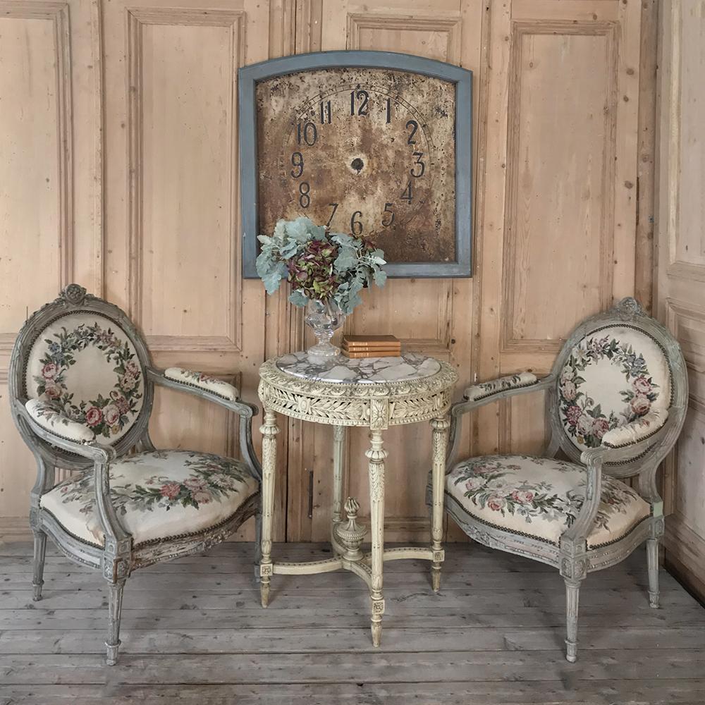 19th century Italian Louis XVI painted marble-top end table is a superlative study in the classical form, with round shape, pinwheel style stretchers connecting the tapered and fluted legs, and lavish foliate and crest motifs on the apron. Highly