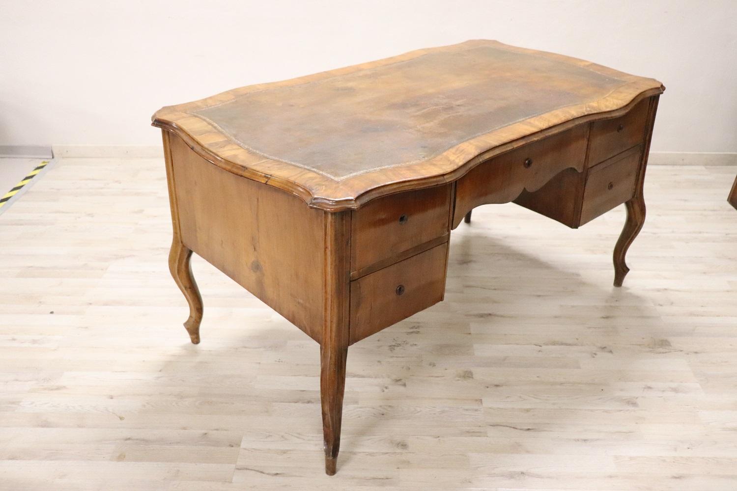 Majestic antique Italian louis XV style large writing desk. Rare and precious walnut wood. Comfortable size for a practical use. The desk has elegant elegant wavy legs. Equipped with five practical drawers. The top is lined in original brown leather