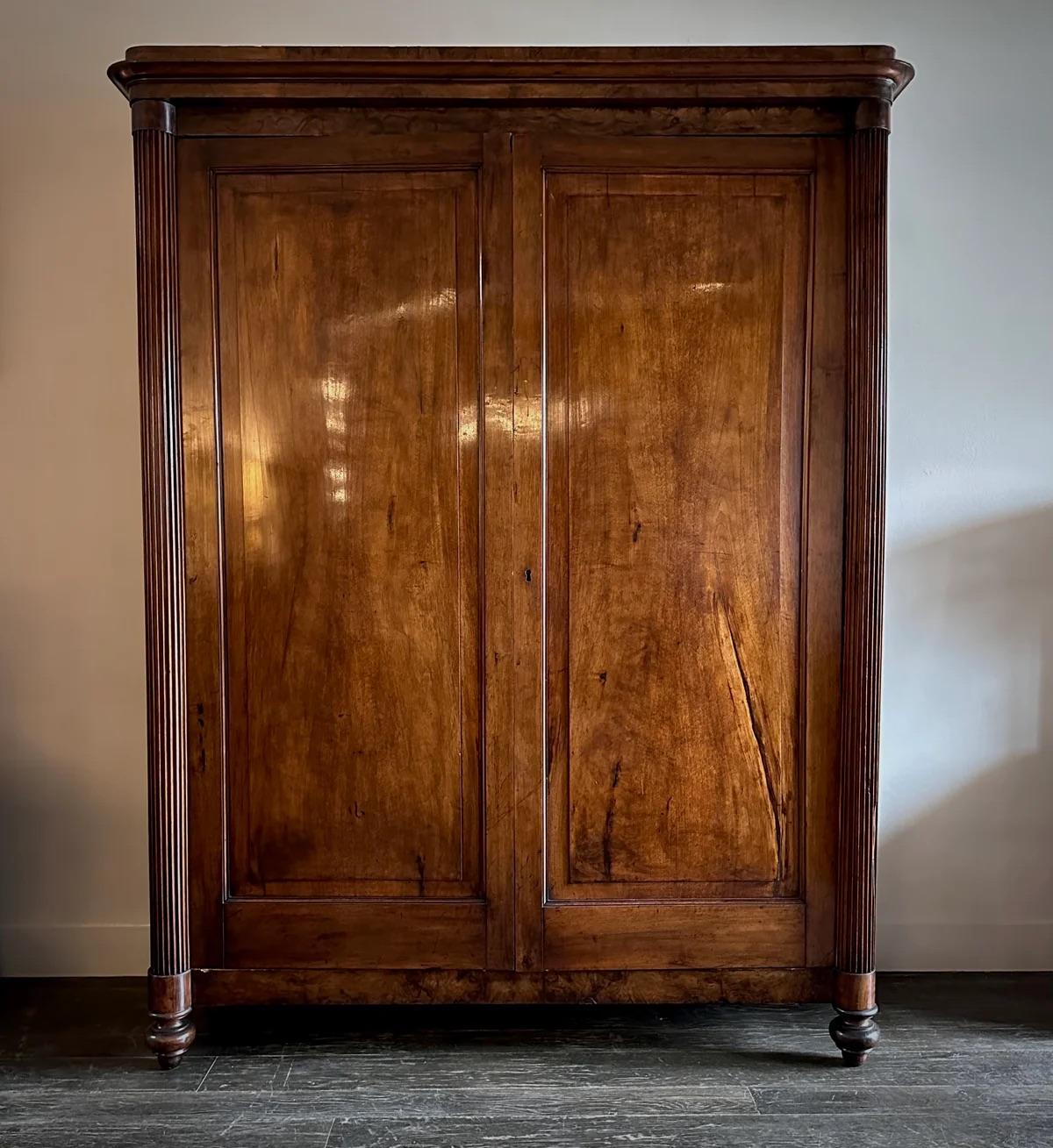 19th-century Italian mahogany armoire with simple, classic lines. This stately piece stands on carved turnip feet and features two single-paneled doors, each flanked by a slim columnar balustrade. The architectural elegance of the balustrades adds a