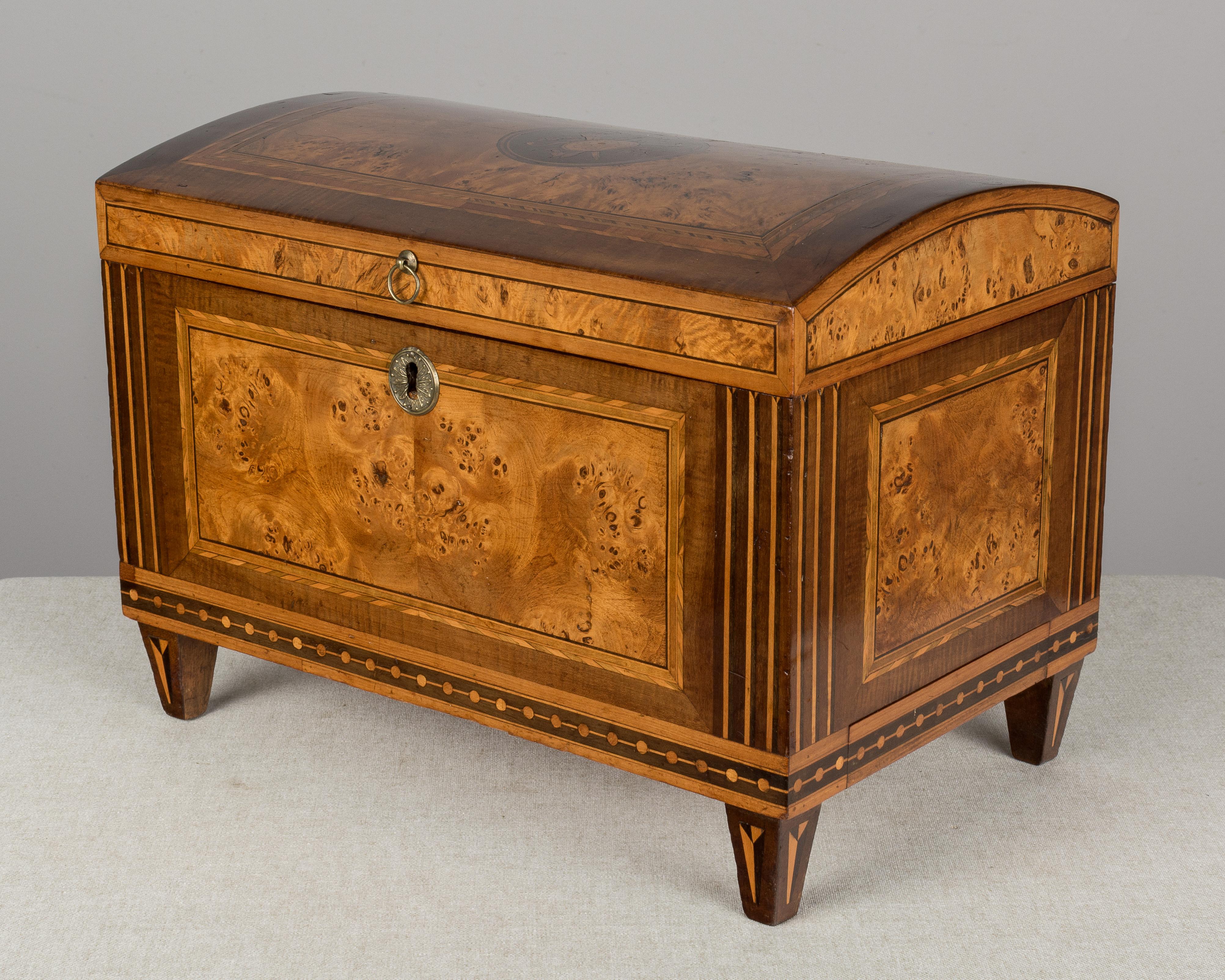 An early 19th century miniature Italian coffer, or hinged box, made of solid walnut with marquetry inlay of various woods and bookmatched bird's-eye maple veneer. The design on the top of the box indicates this was likely a wedding gift: the